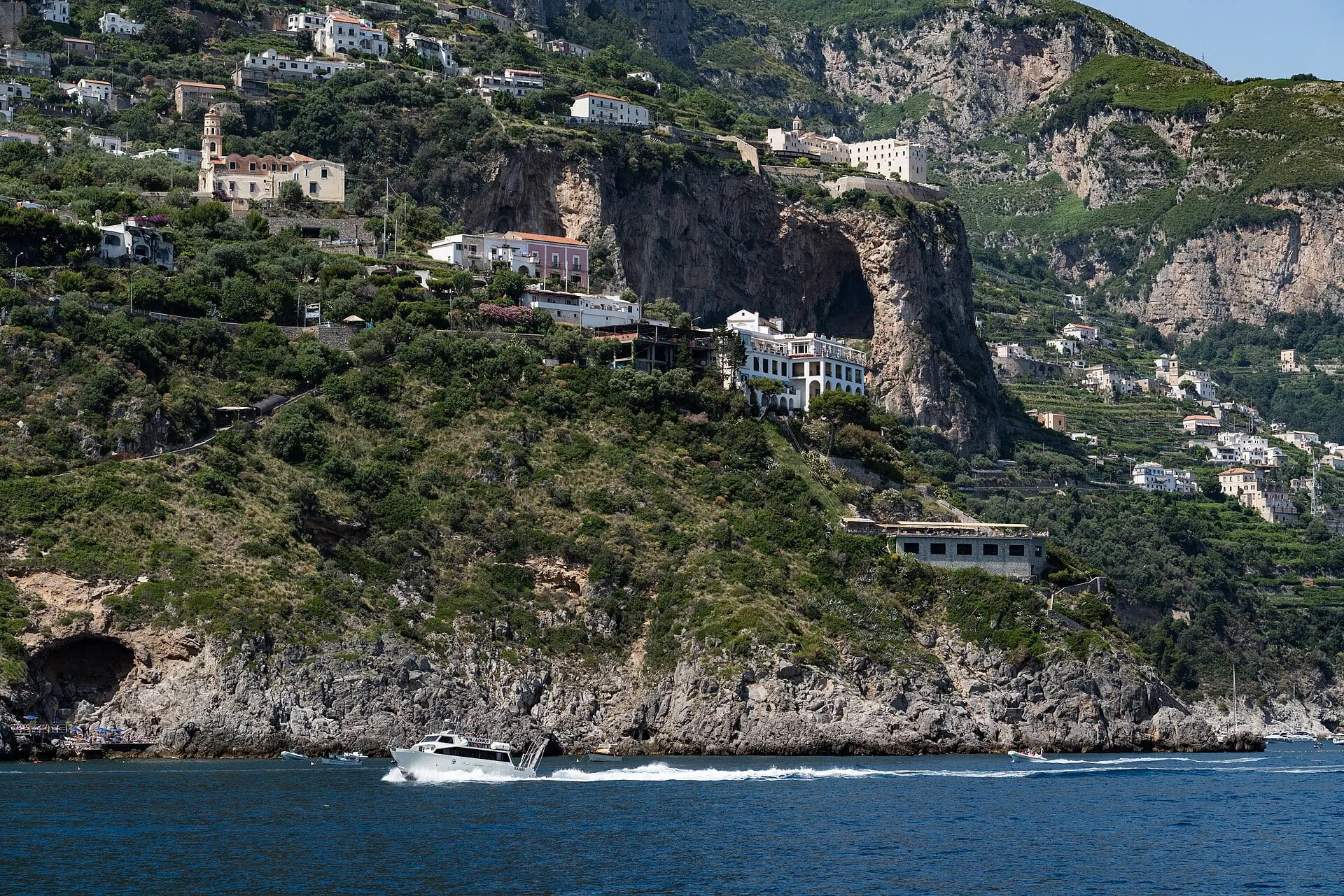 A boat cutting along the cliffs of the Amalfi Coast between Positano and Amalfi