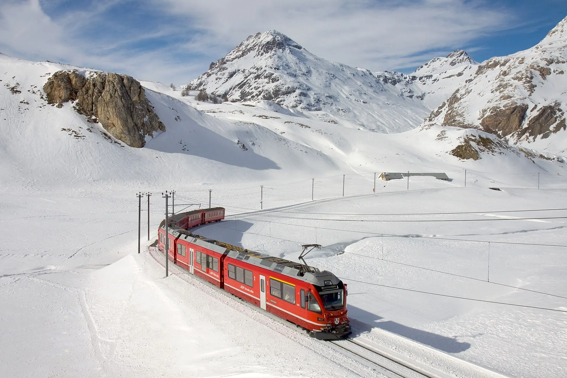 A red Allegra train climbing through deep winter snow between Bernina Lagalb and Ospizio Bernina.