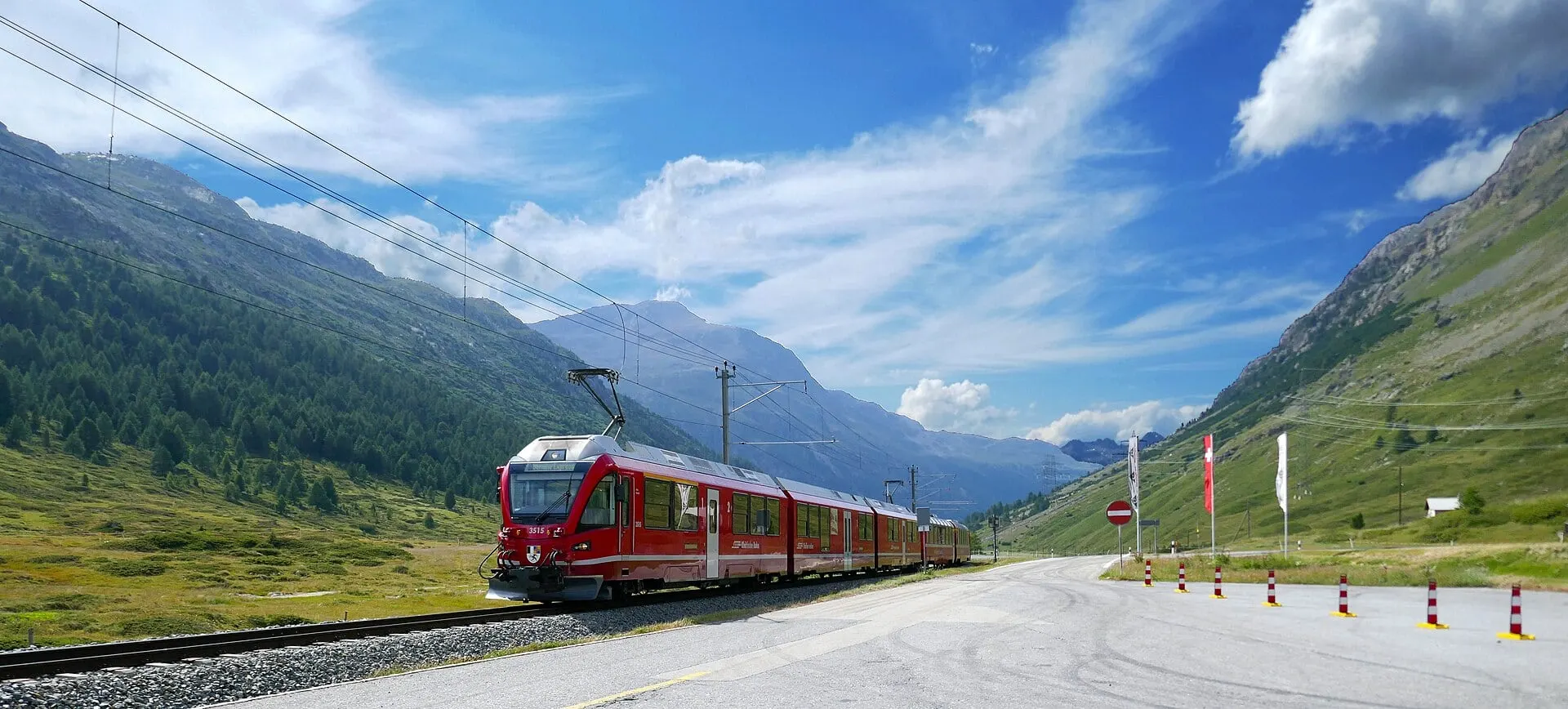 The Bernina Express approaching Bernina Diavolezza station in Val Bernina on a sunny summer day.