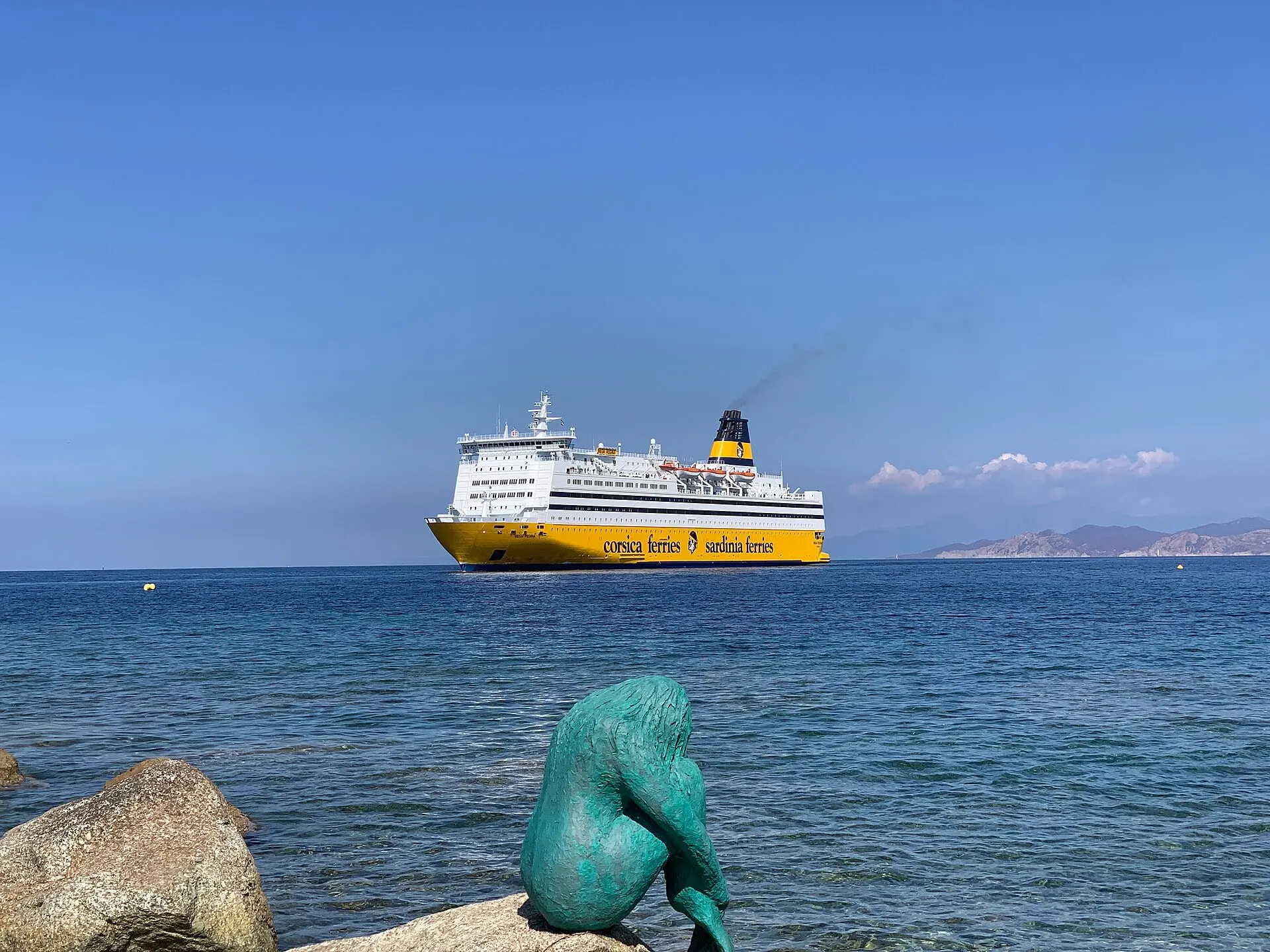 The Corsica Ferries ship Mega Regina arriving at L'Île-Rousse across a calm blue sea