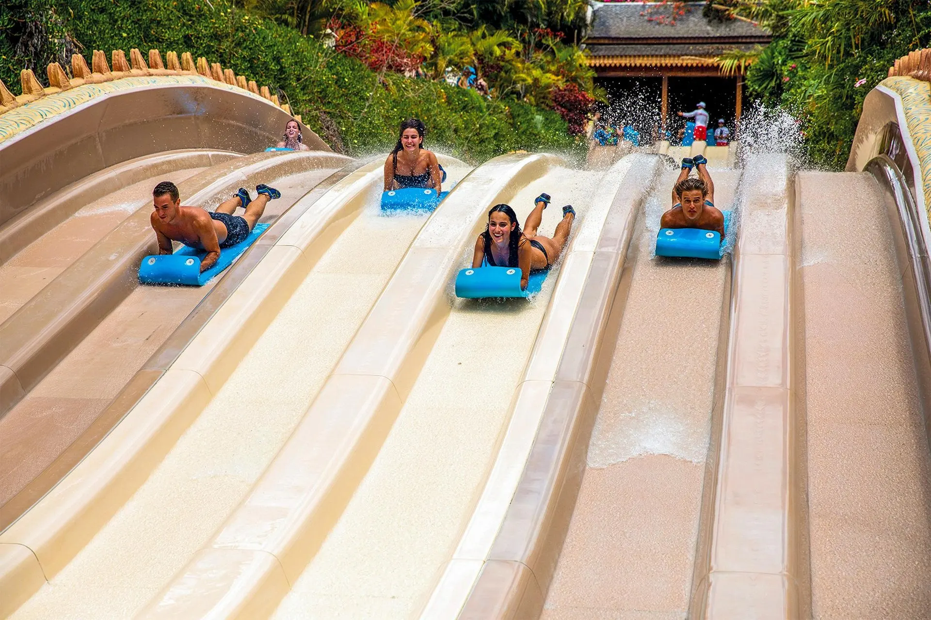 Riders racing head first down a multi-lane slide at Siam Park