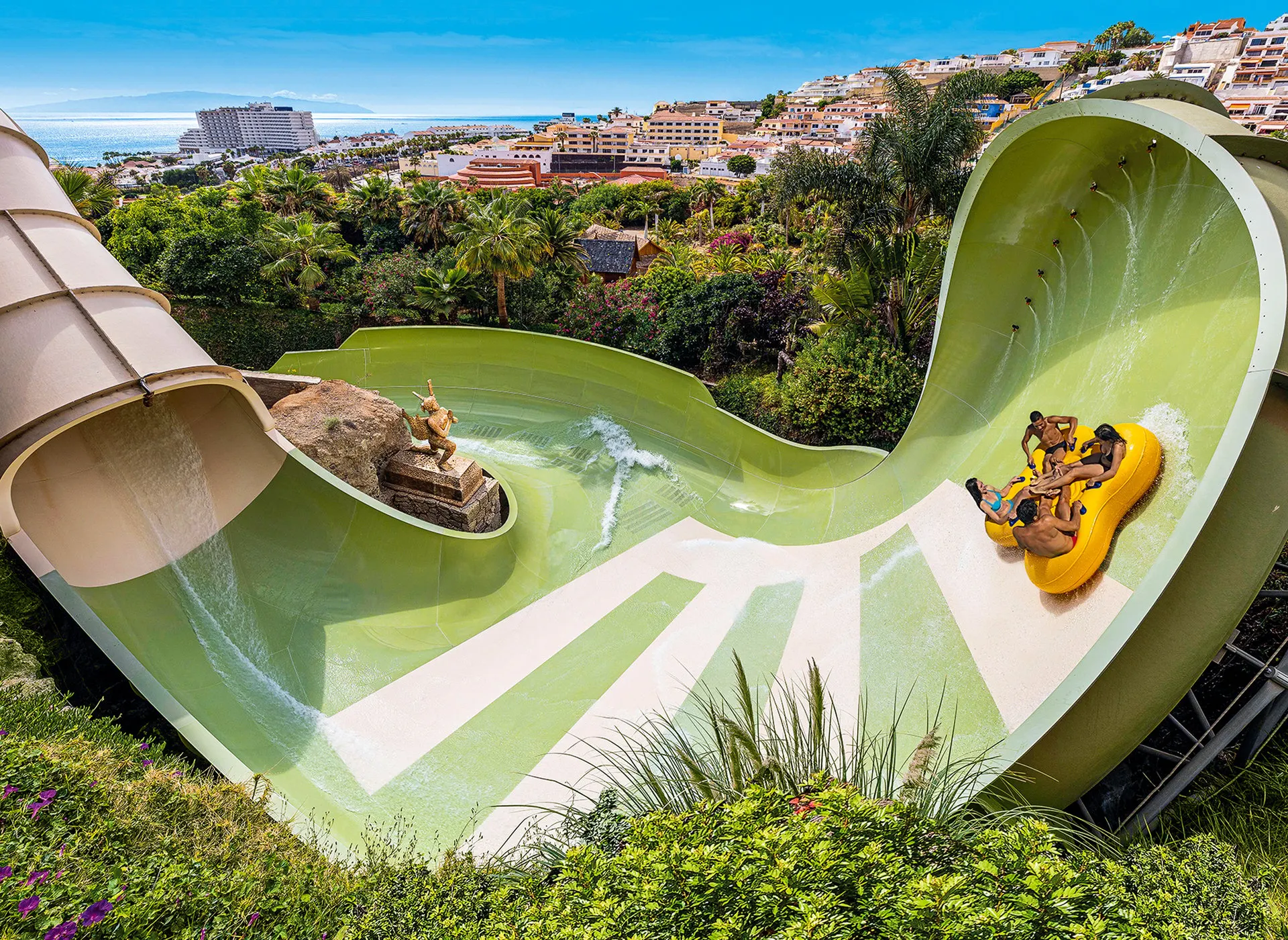 A family tube in a giant funnel slide, with the coast behind