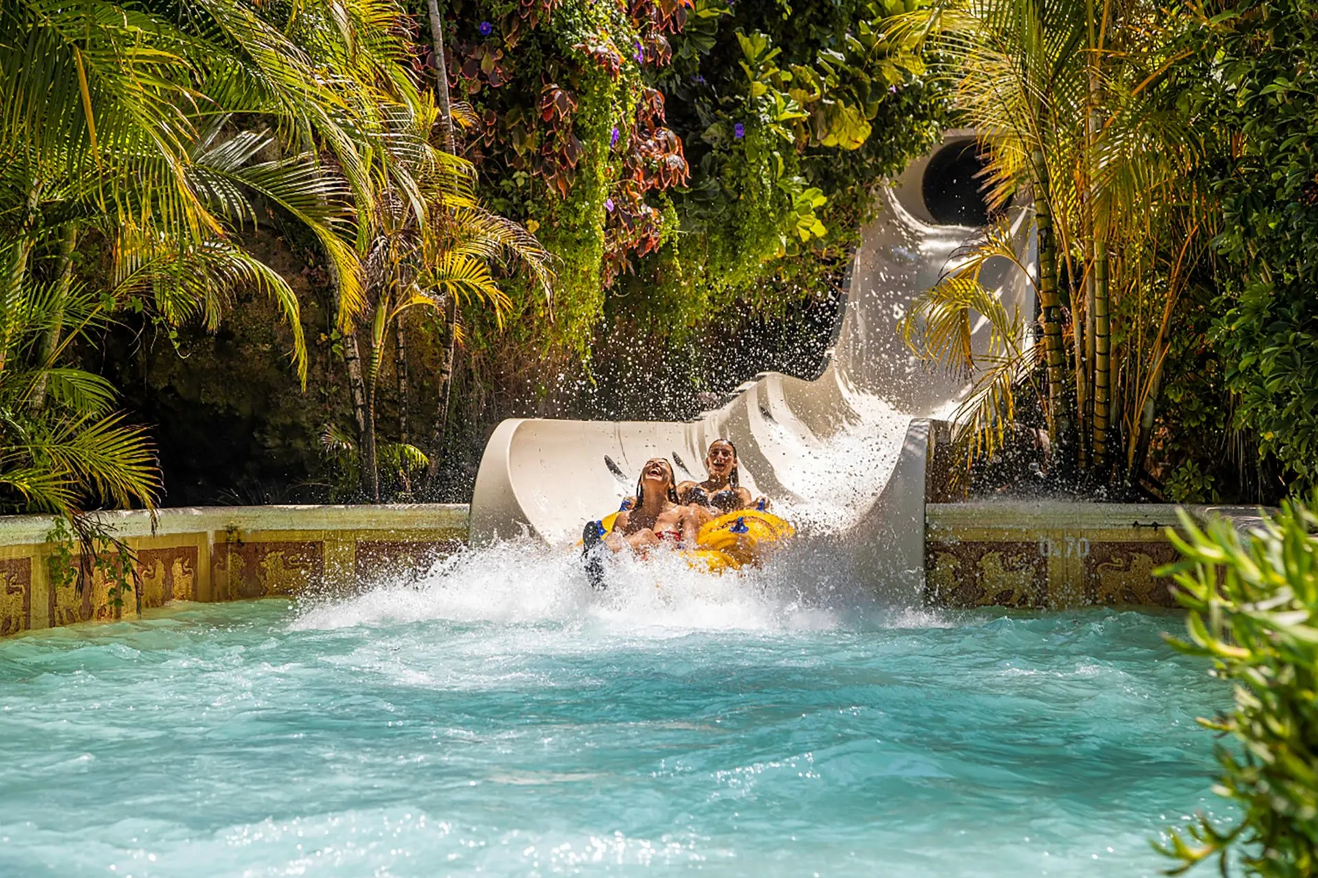 A rider splashing out of a slide into a pool