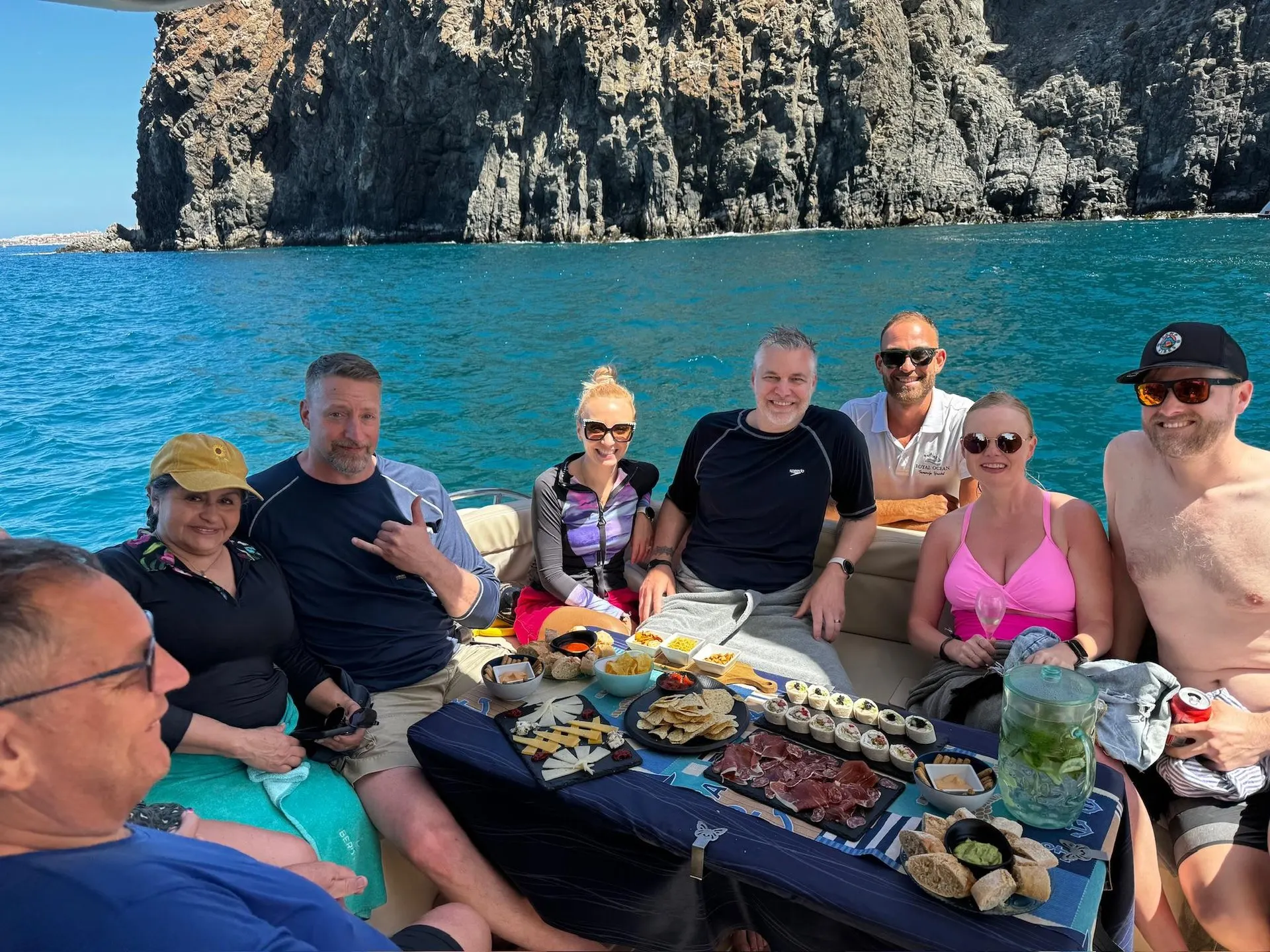 Guests with snacks and drinks on board, anchored below the cliffs