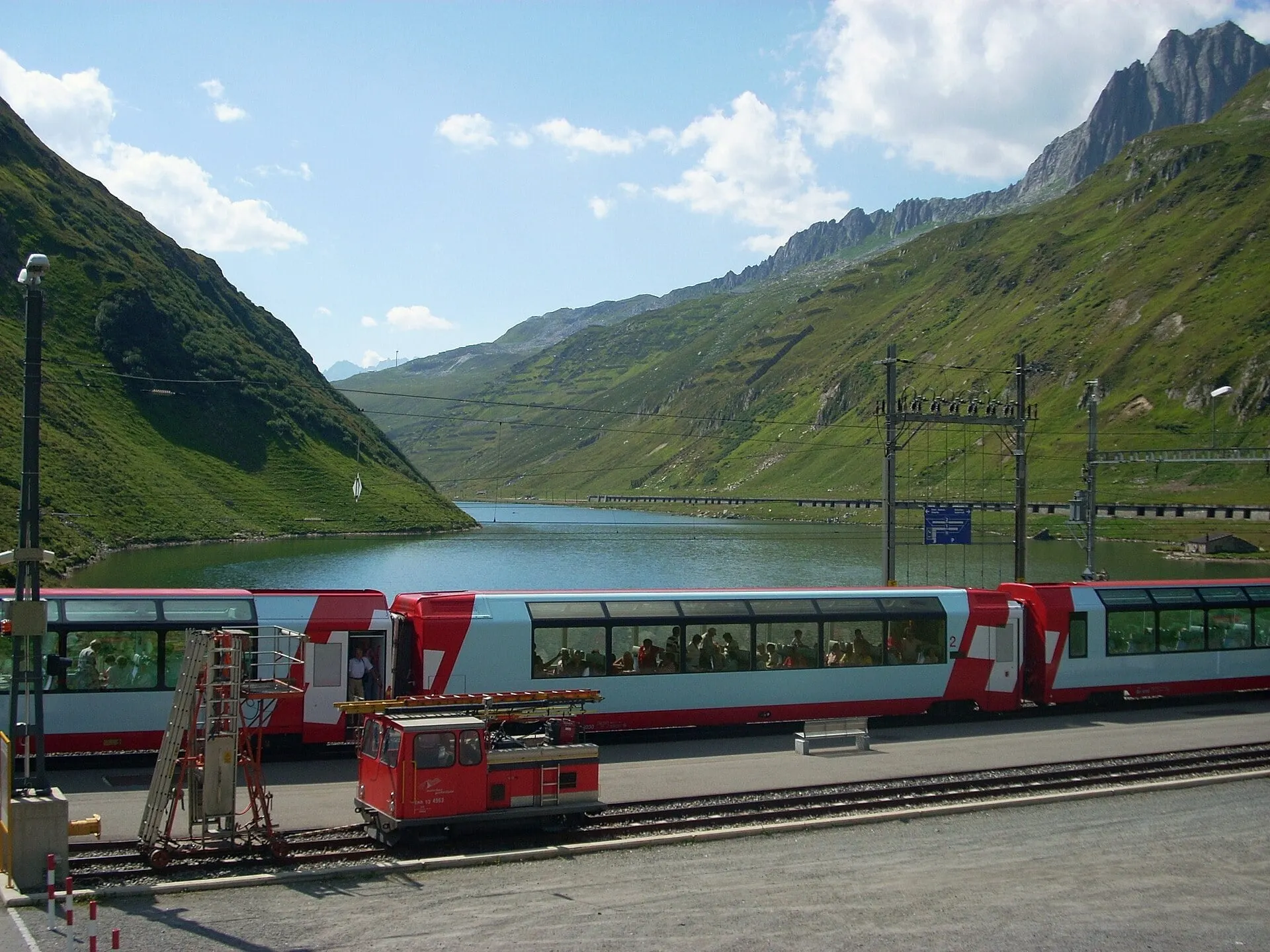 Glacier Express coaches at Oberalppass station beside the Oberalpsee lake