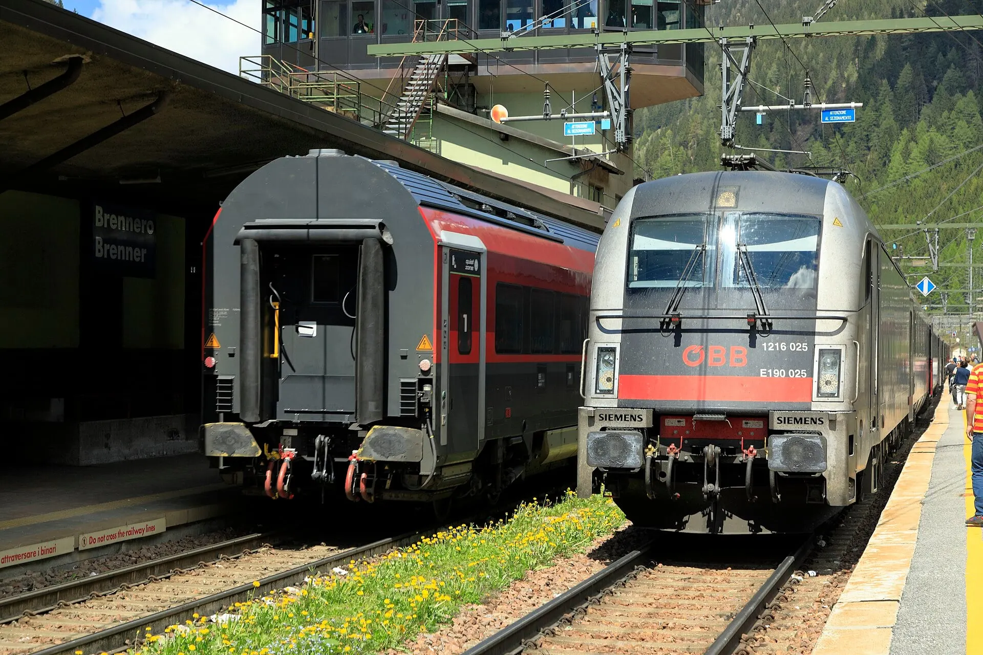 An ÖBB locomotive and red passenger coaches at the platforms of Brennero station