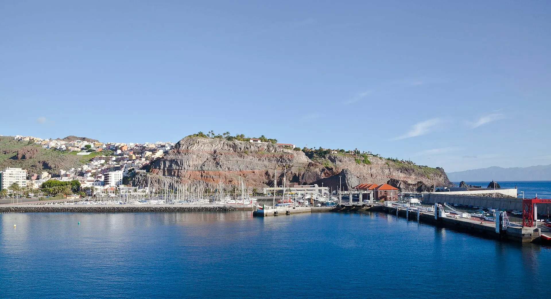 The harbour of San Sebastián de La Gomera and marina below its red cliffs, with the ferry quay on the right.