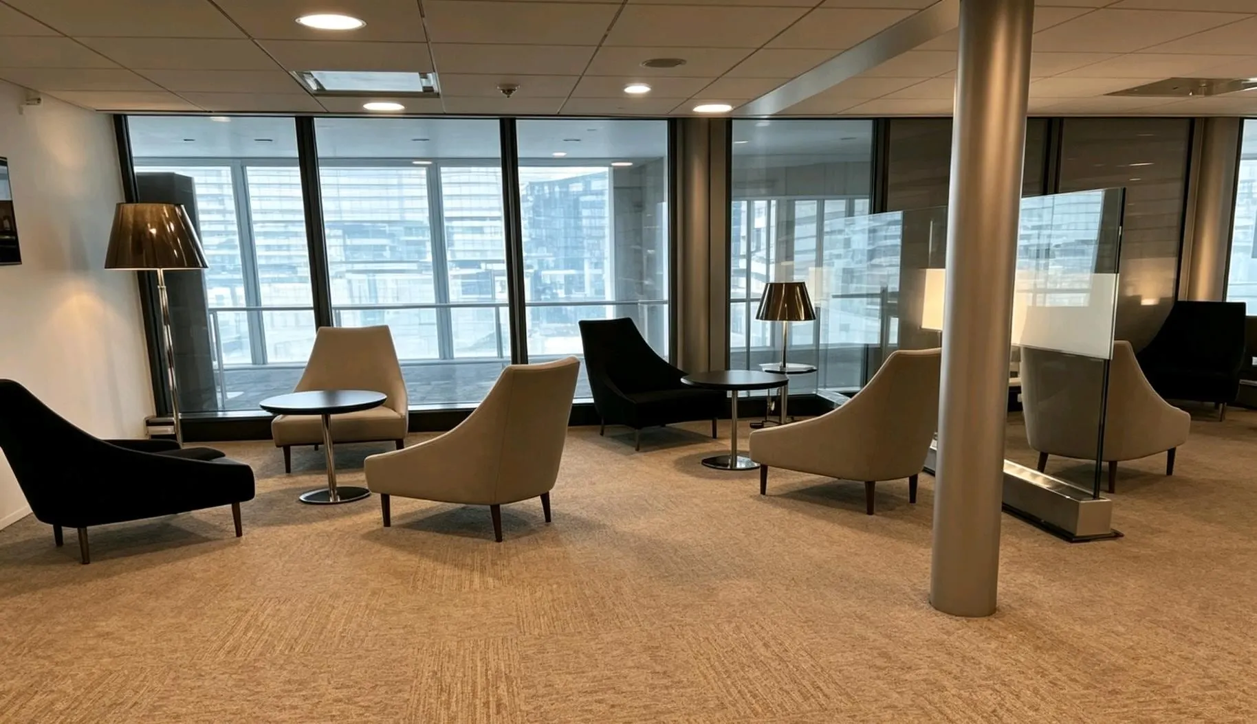 Quiet seating area with beige armchairs, side tables and floor lamps by the windows