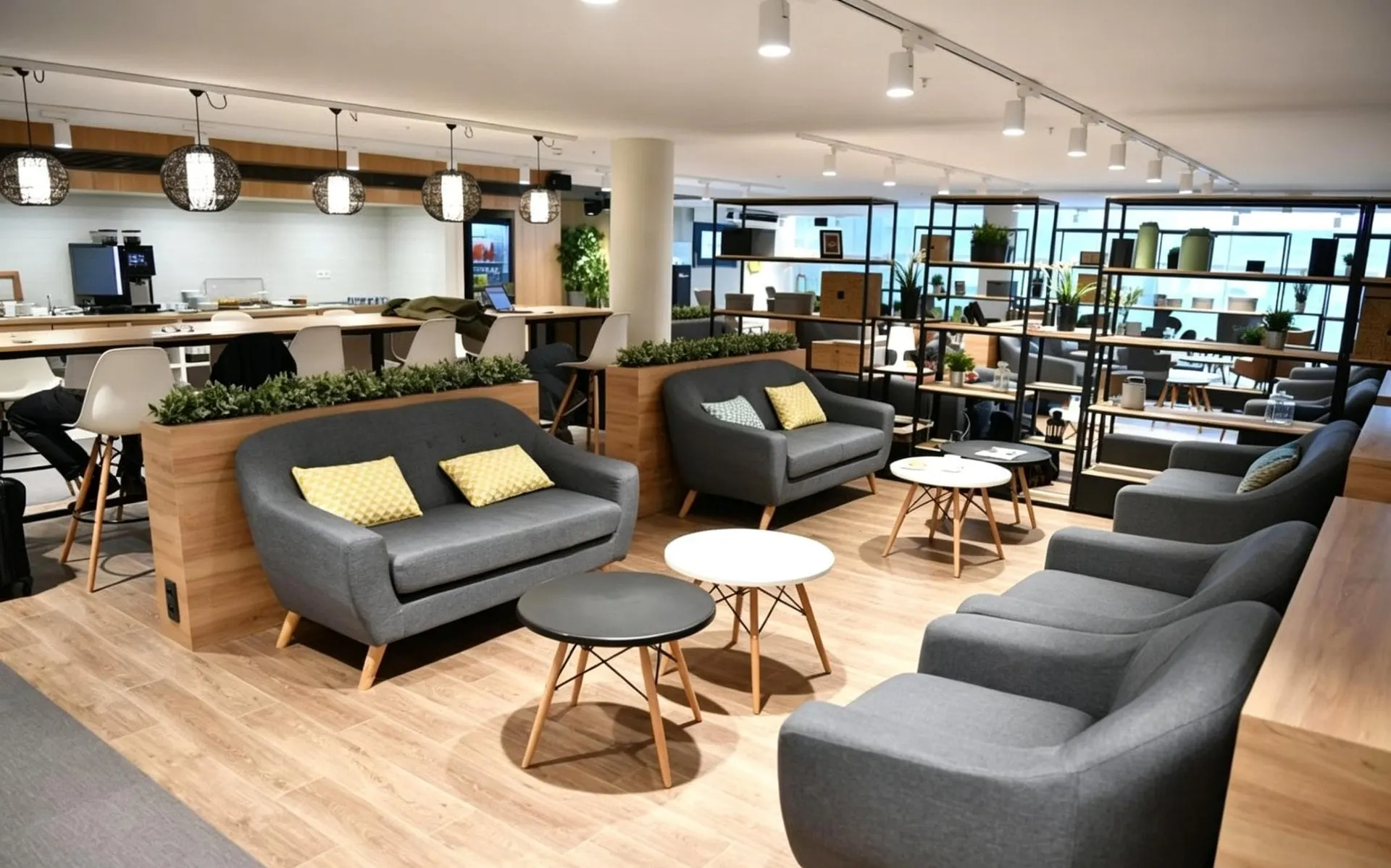 Grey sofas and armchairs with yellow cushions, round white tables and a coffee counter