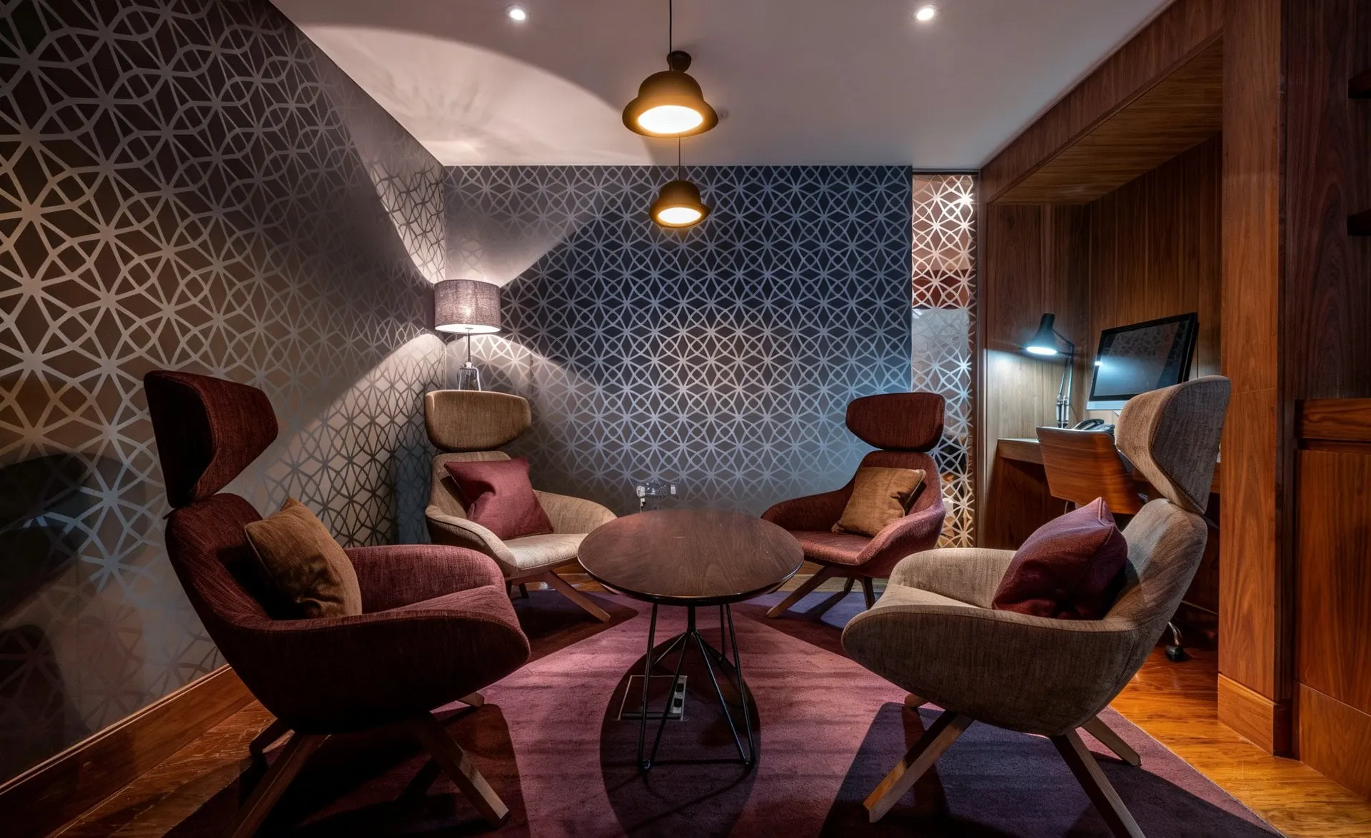 Four high-backed armchairs around a small round table under a pendant lamp
