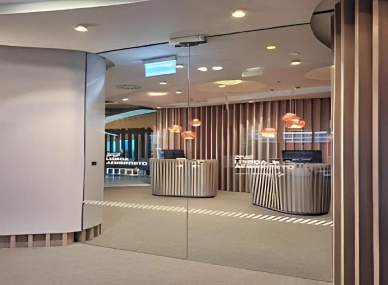Glass entrance to the ANA Lounge with two reception desks and orange pendant lamps behind