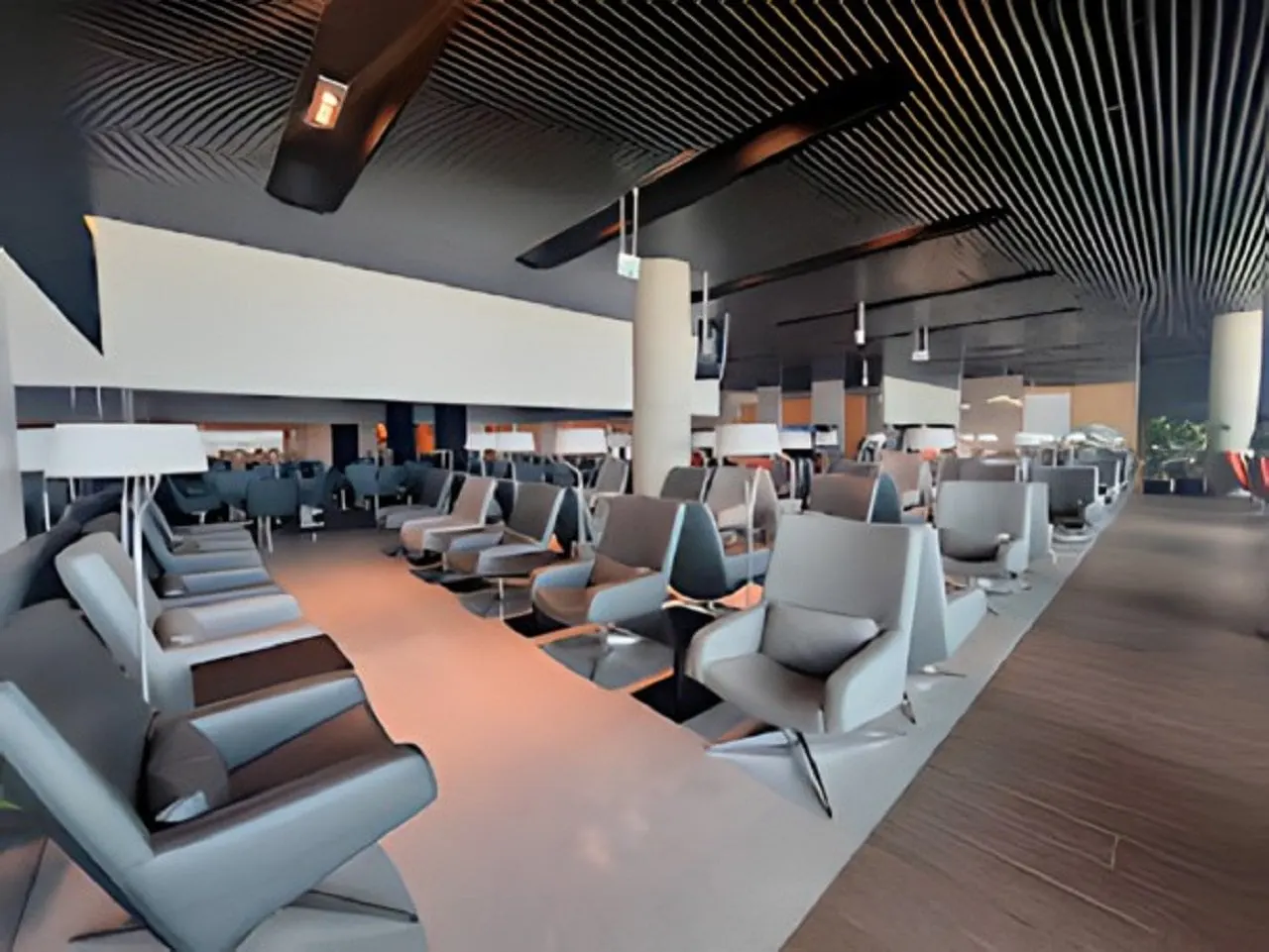 Rows of grey reclining lounge chairs with reading lamps under a dark slatted ceiling in the ANA Lounge, Lisbon