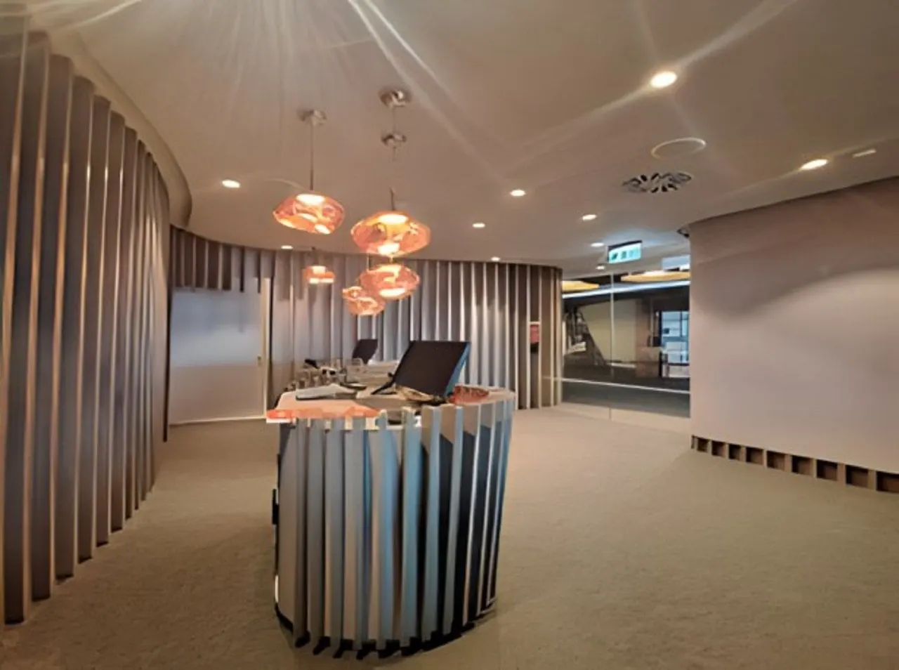 Curved reception desk with copper pendant lights and wooden slatted walls