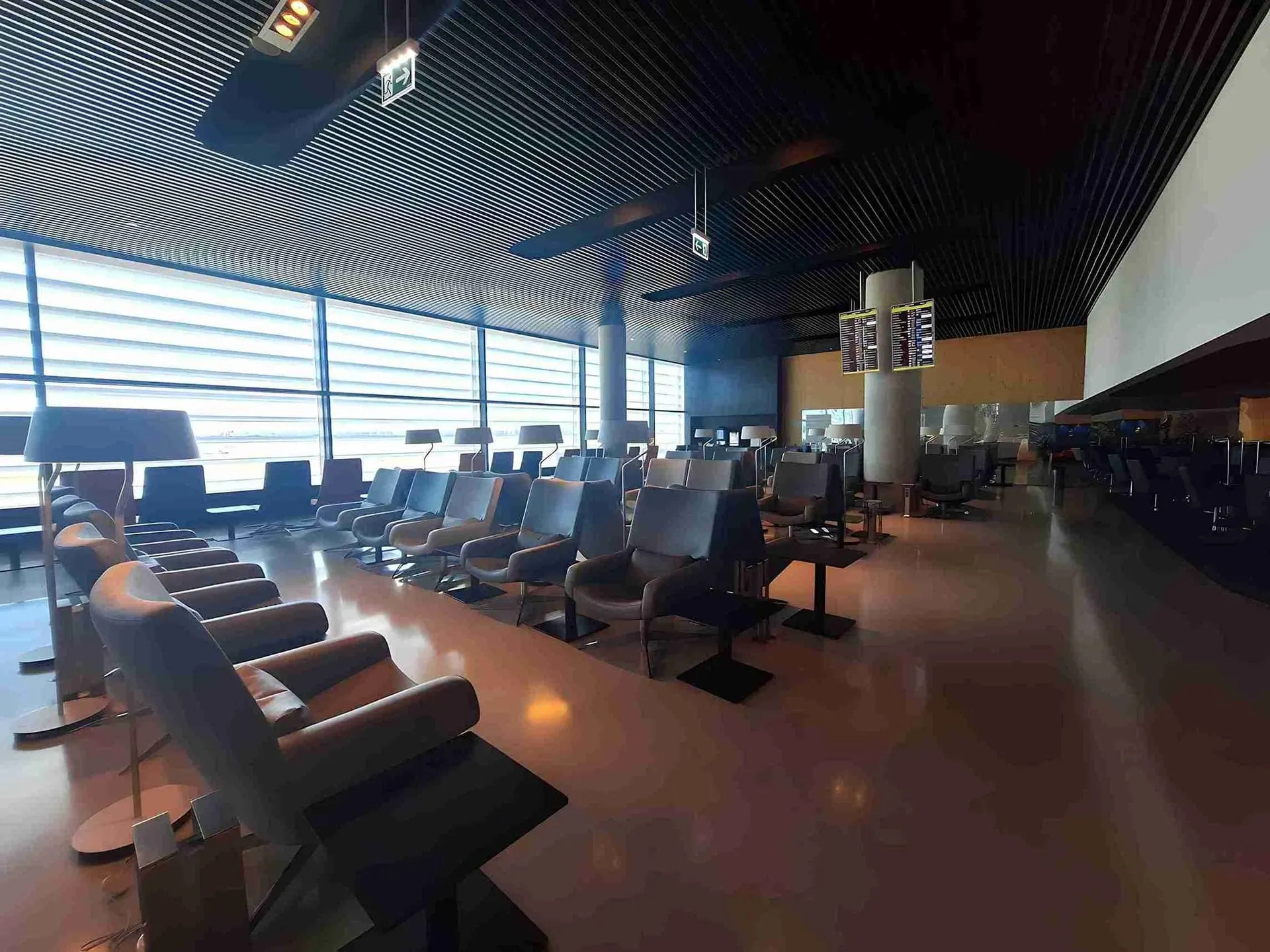 Armchairs lined up along tall windows with daylight coming through the blinds