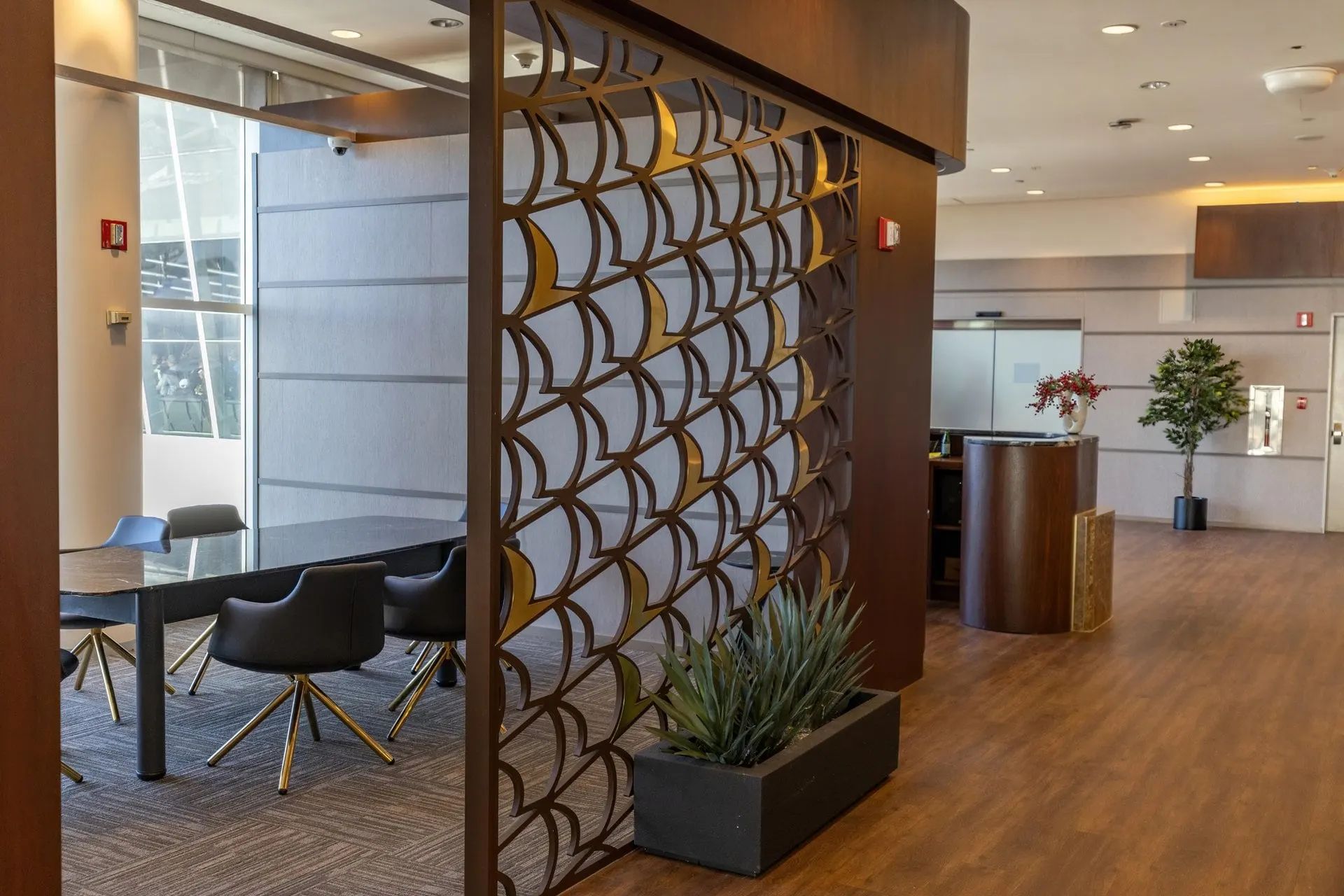 Meeting table with leather chairs behind a bronze patterned screen and potted plants
