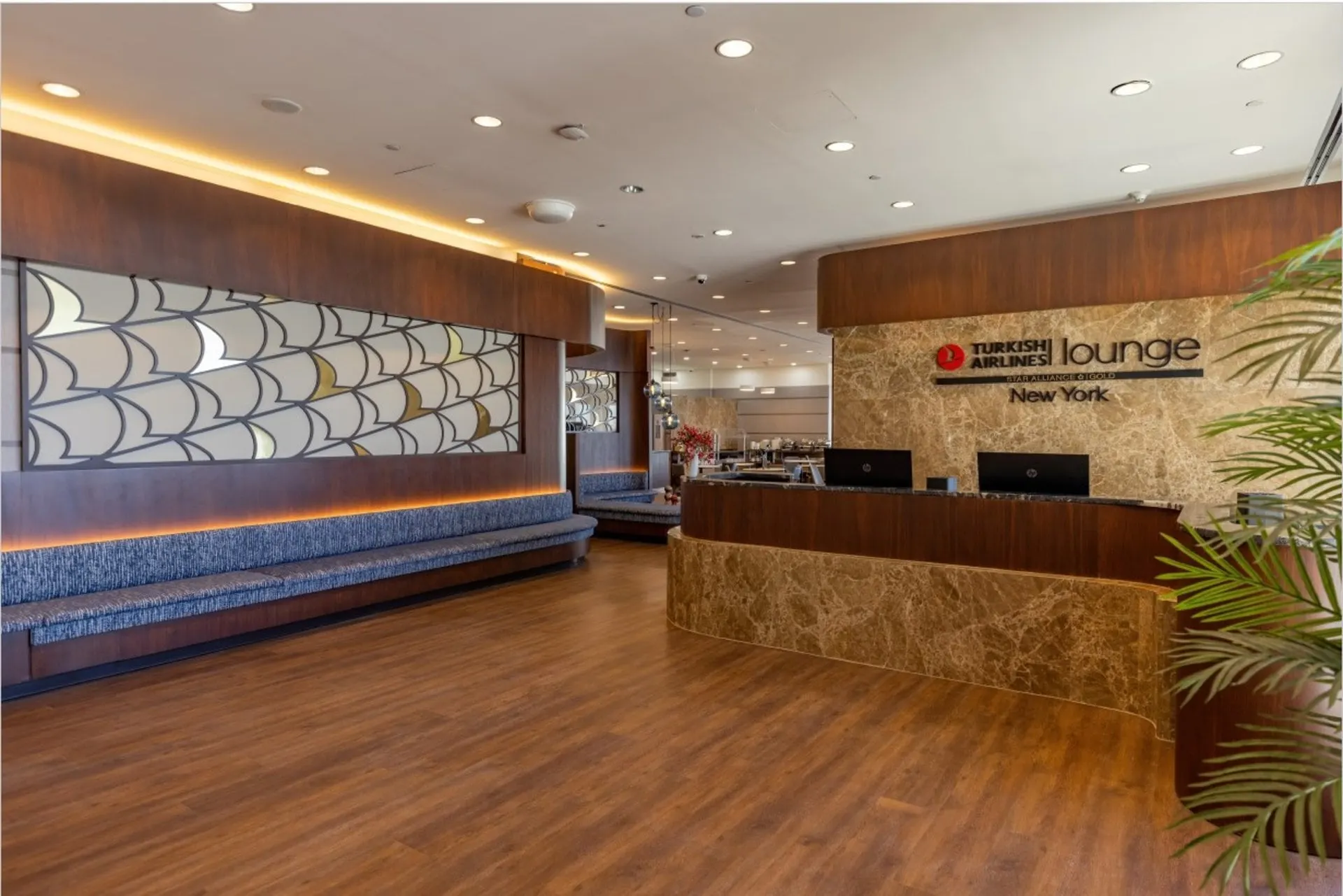 Lounge reception with a wooden desk, a long banquette and a decorative wave-pattern screen