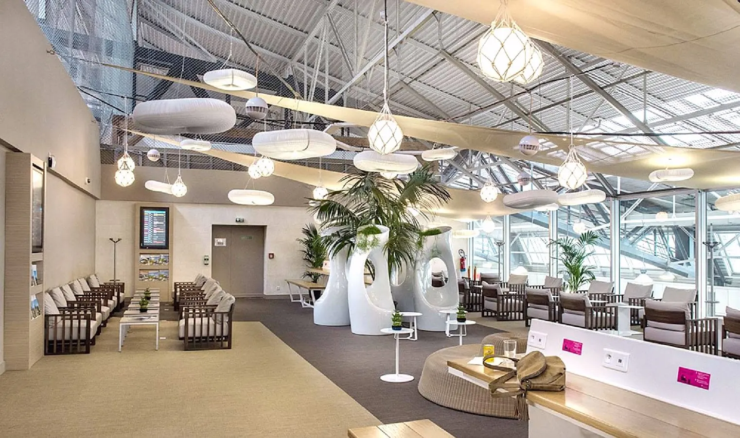 Lounge with white sculpted seating pods, palms and hanging lantern lights