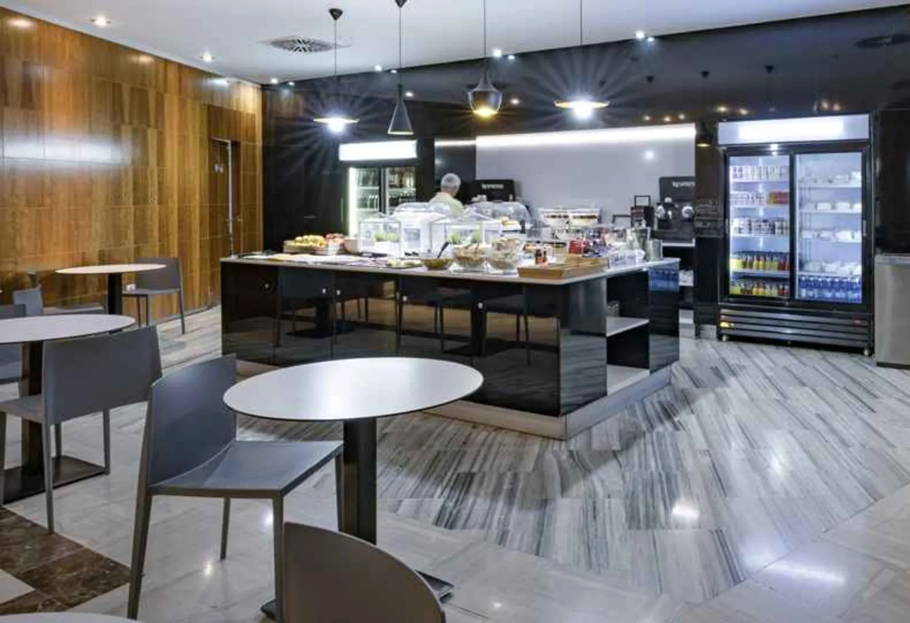 Îlot de buffet en libre-service avec réfrigérateurs à boissons, tables rondes de café et chaises grises