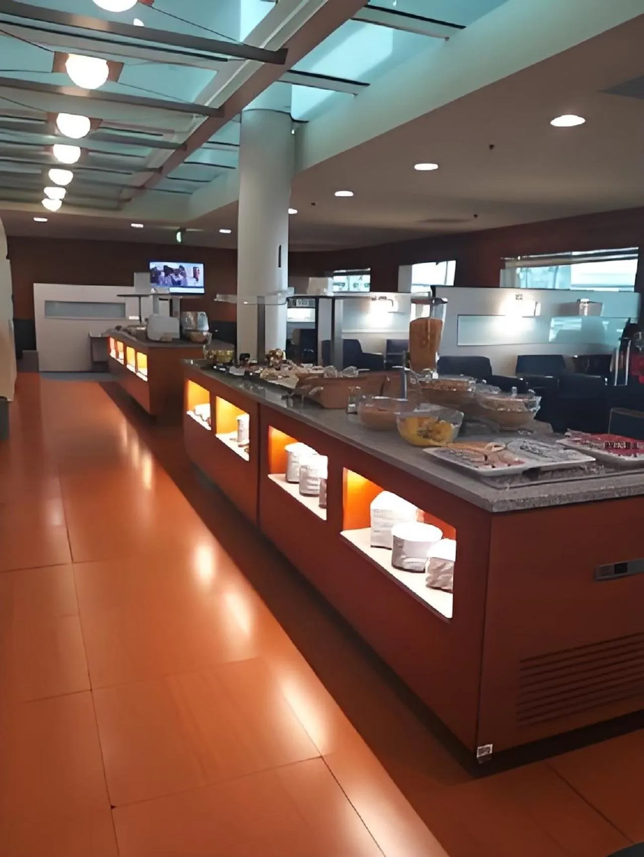Buffettheke mit Tellern, Obst und Snacks an einem orange beleuchteten Möbel