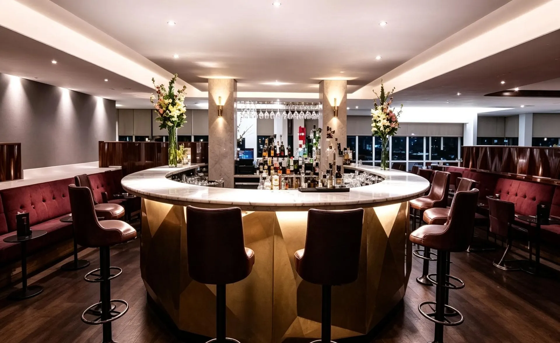 Round gold-fronted bar with bottles on the back shelves and burgundy stools around it