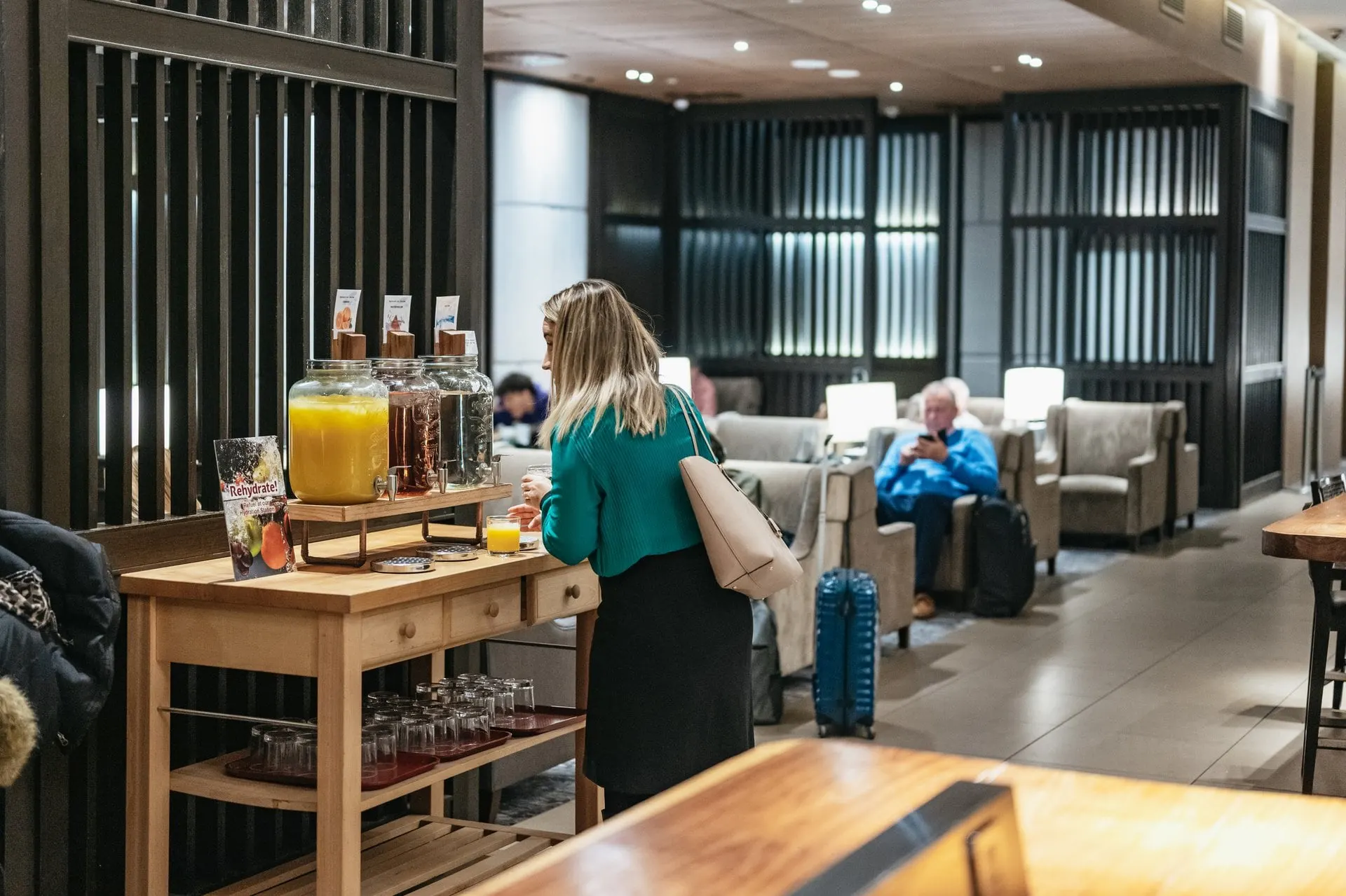 Juice dispensers and glasses on a wooden drinks station, with armchairs behind