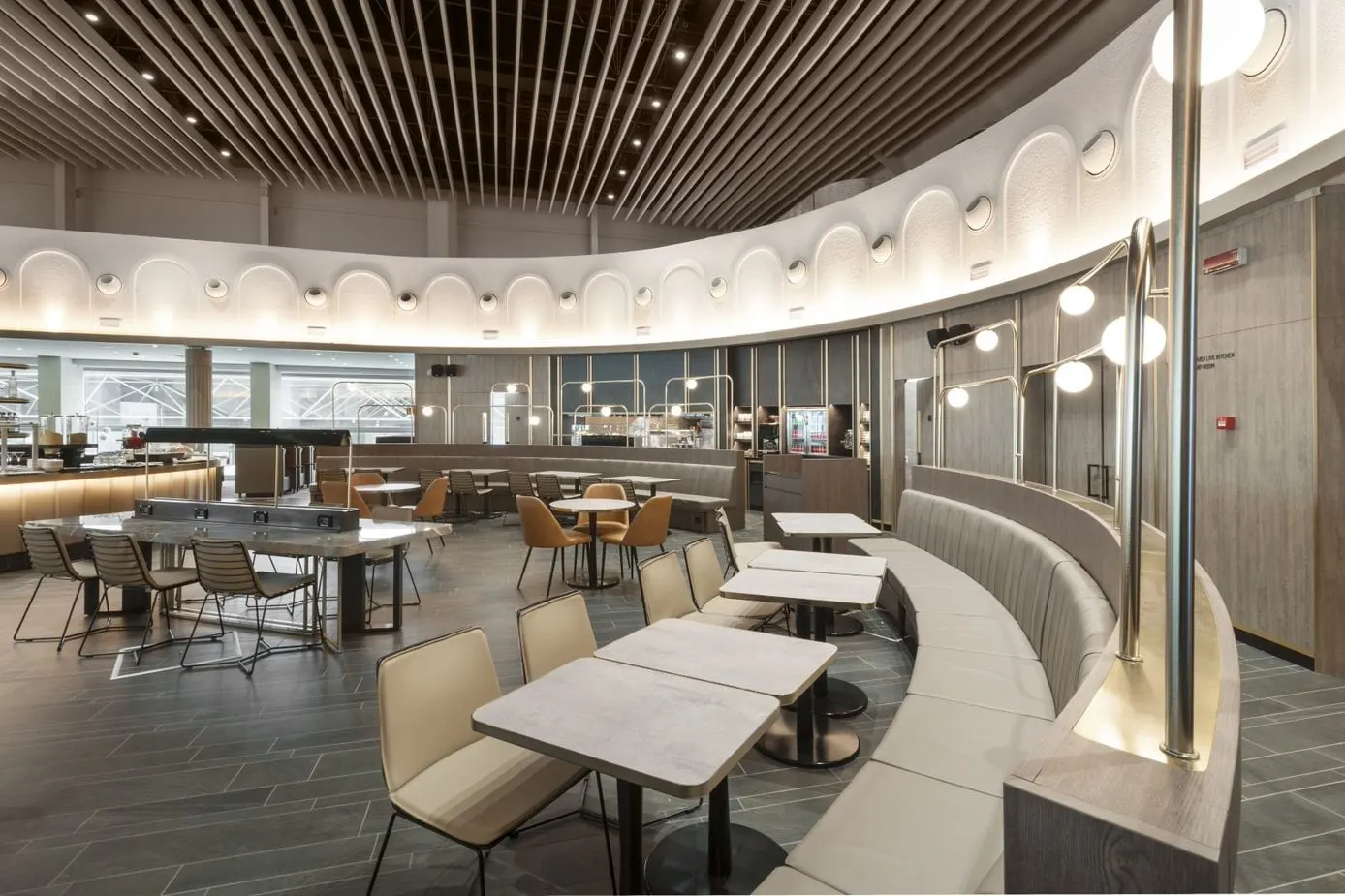 Dining tables and chairs along a curved banquette under a wooden slatted ceiling