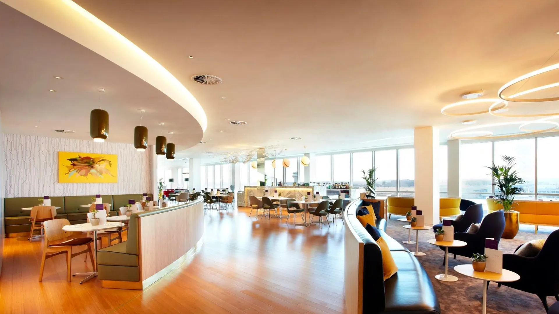 Long lounge with wooden floors, booths and tables stretching towards the windows