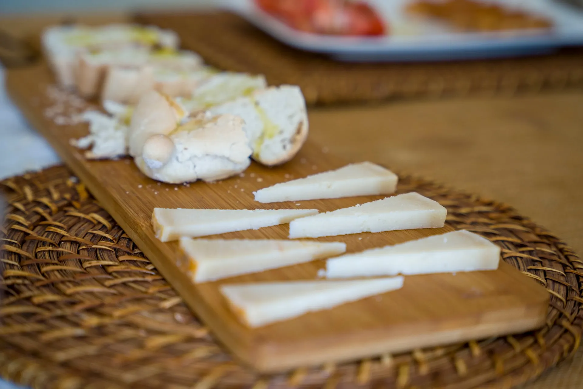 Wedges of goat cheese on a wooden board, with bread and olive oil behind