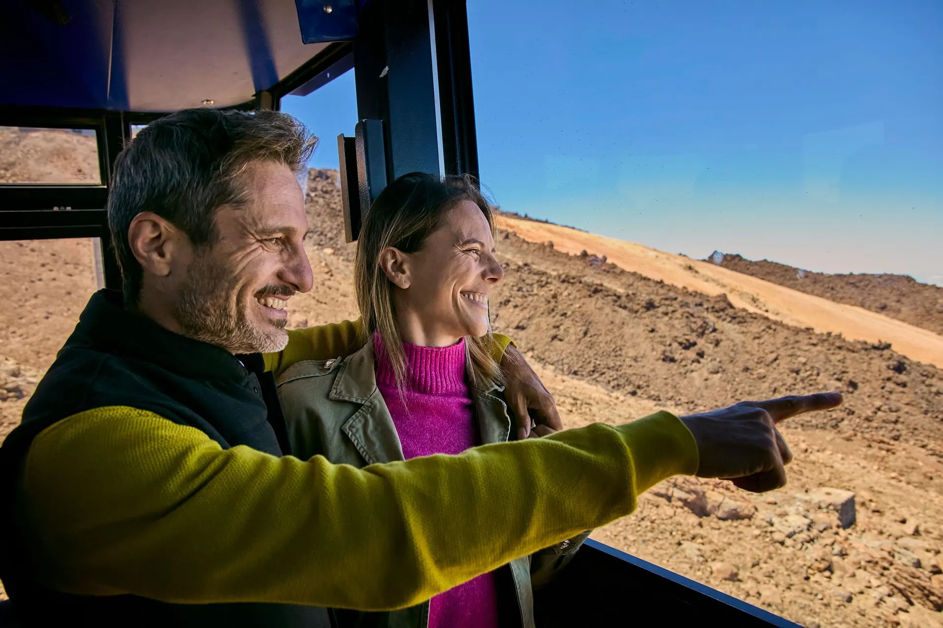 Two visitors pointing out the view from inside a Teide cable car cabin