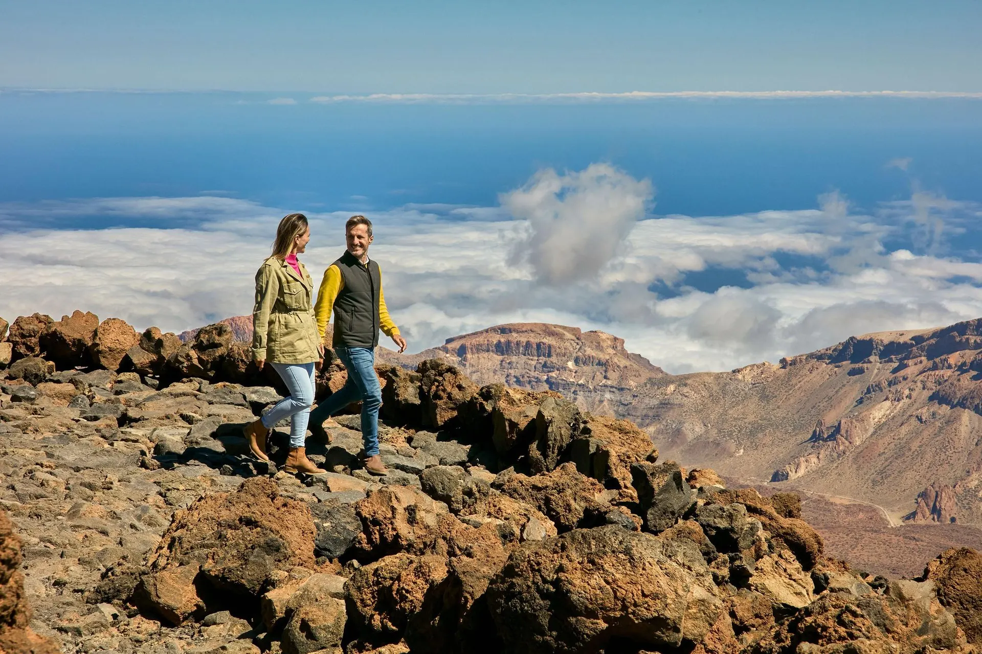 Two hikers on the lava rocks near the upper station, above a sea of cloud