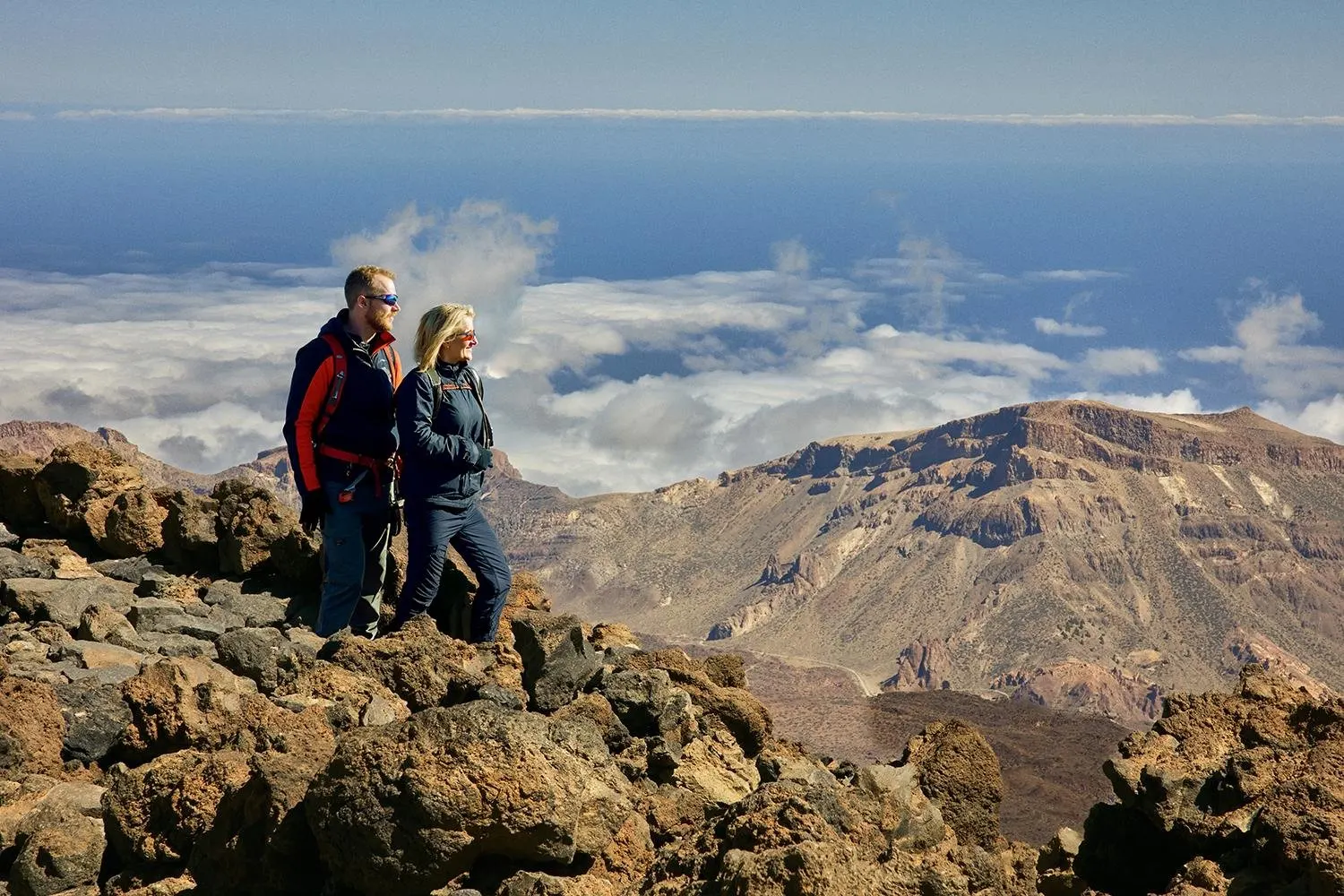 A couple on the rocks at the top, with the sea of cloud and the caldera below