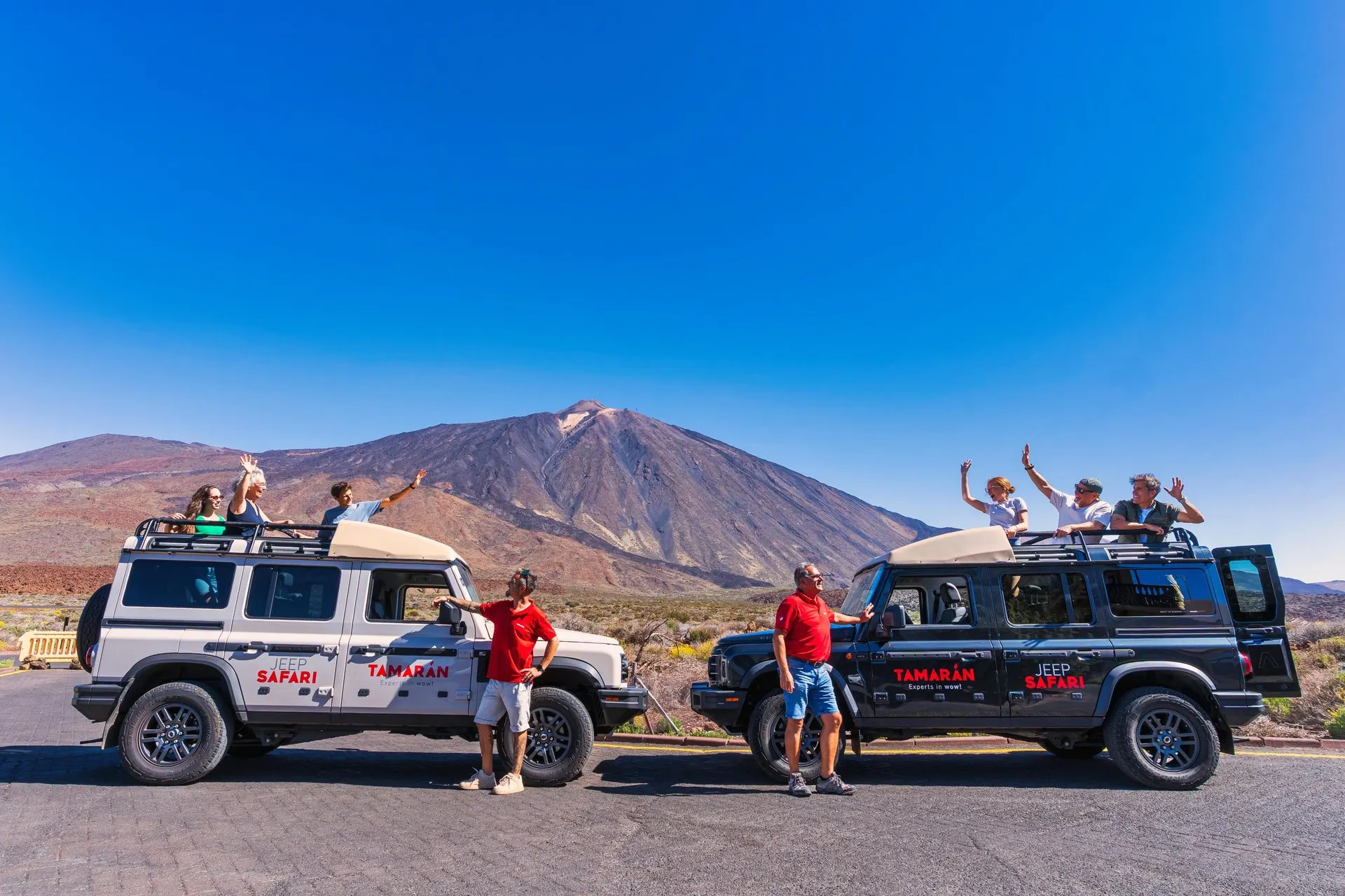 Two safari jeeps parked in Teide National Park with the peak behind