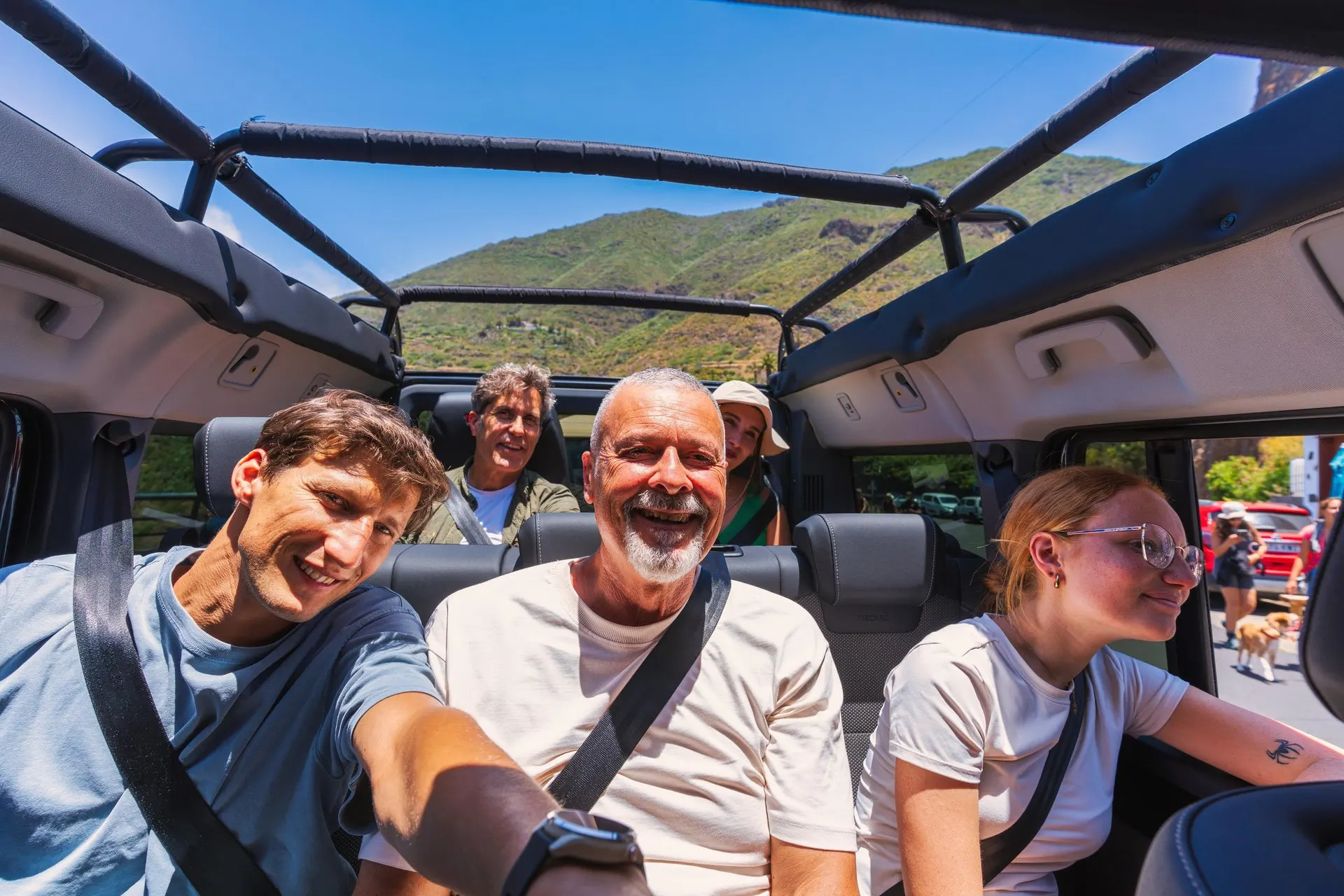 Passengers laughing in the back of an open-topped jeep