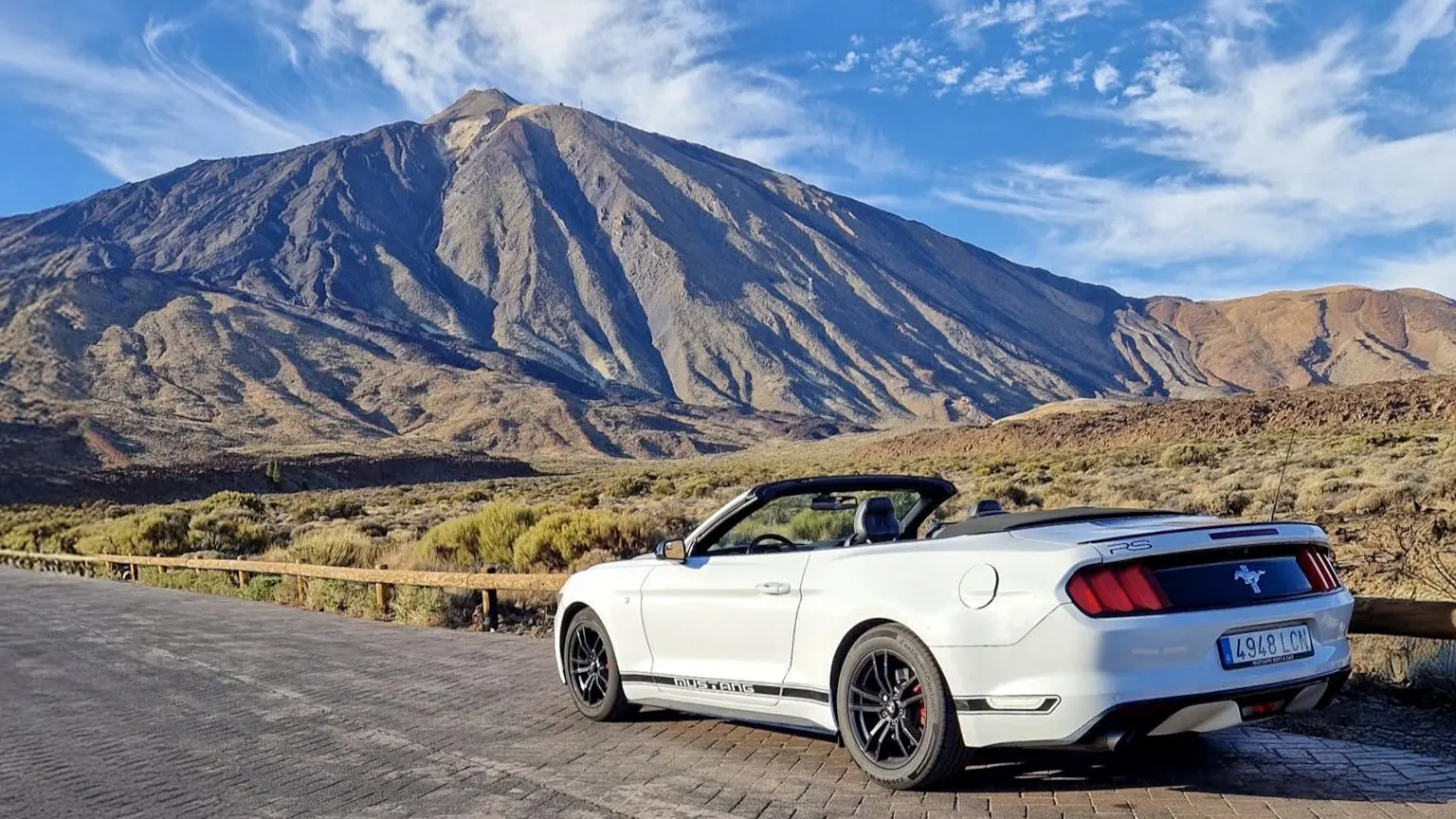 A white Ford Mustang convertible parked in Teide National Park, with Mount Teide behind
