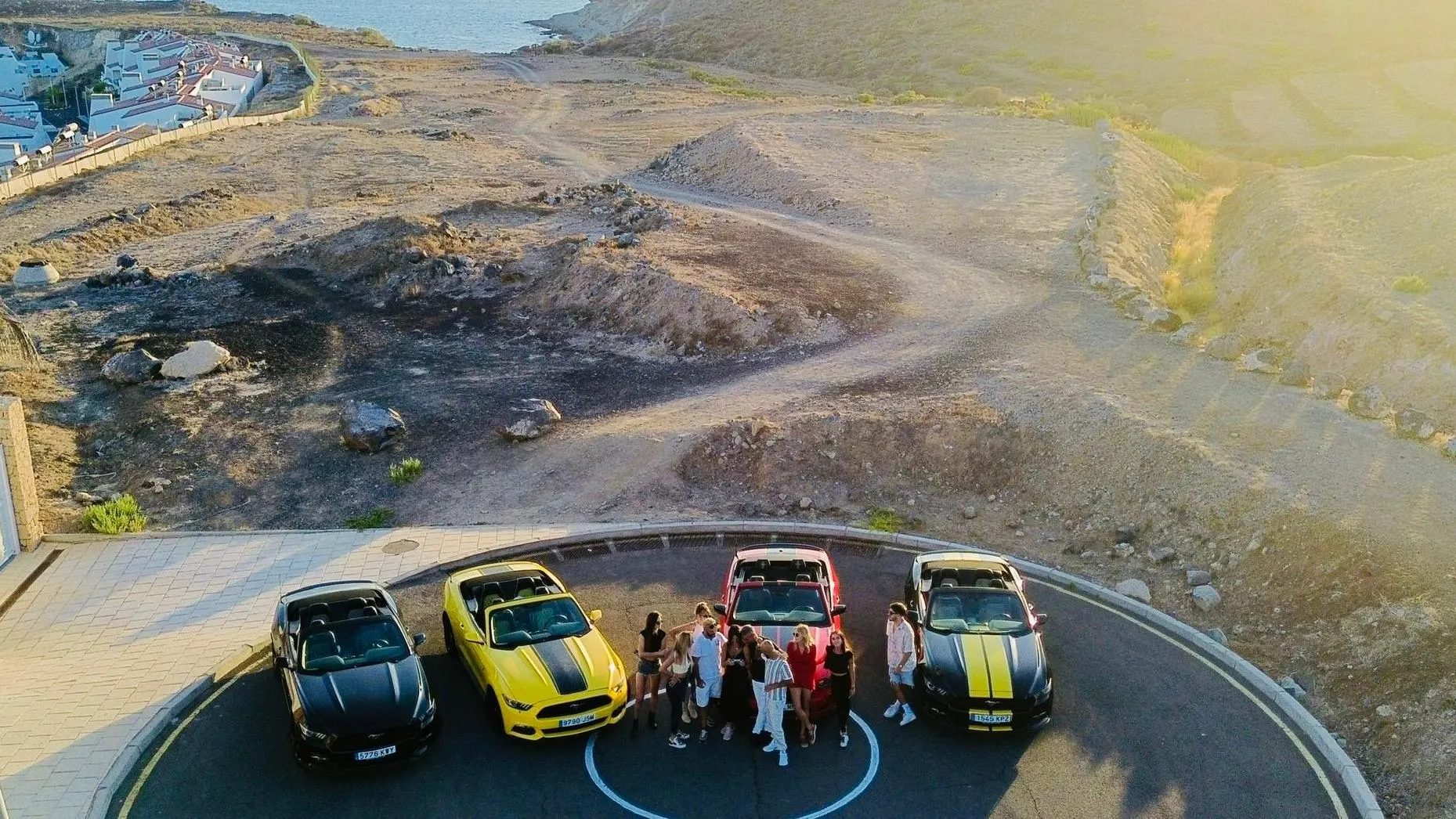 Four Mustang convertibles and their drivers at a roadside viewpoint in the Teide caldera, seen from above