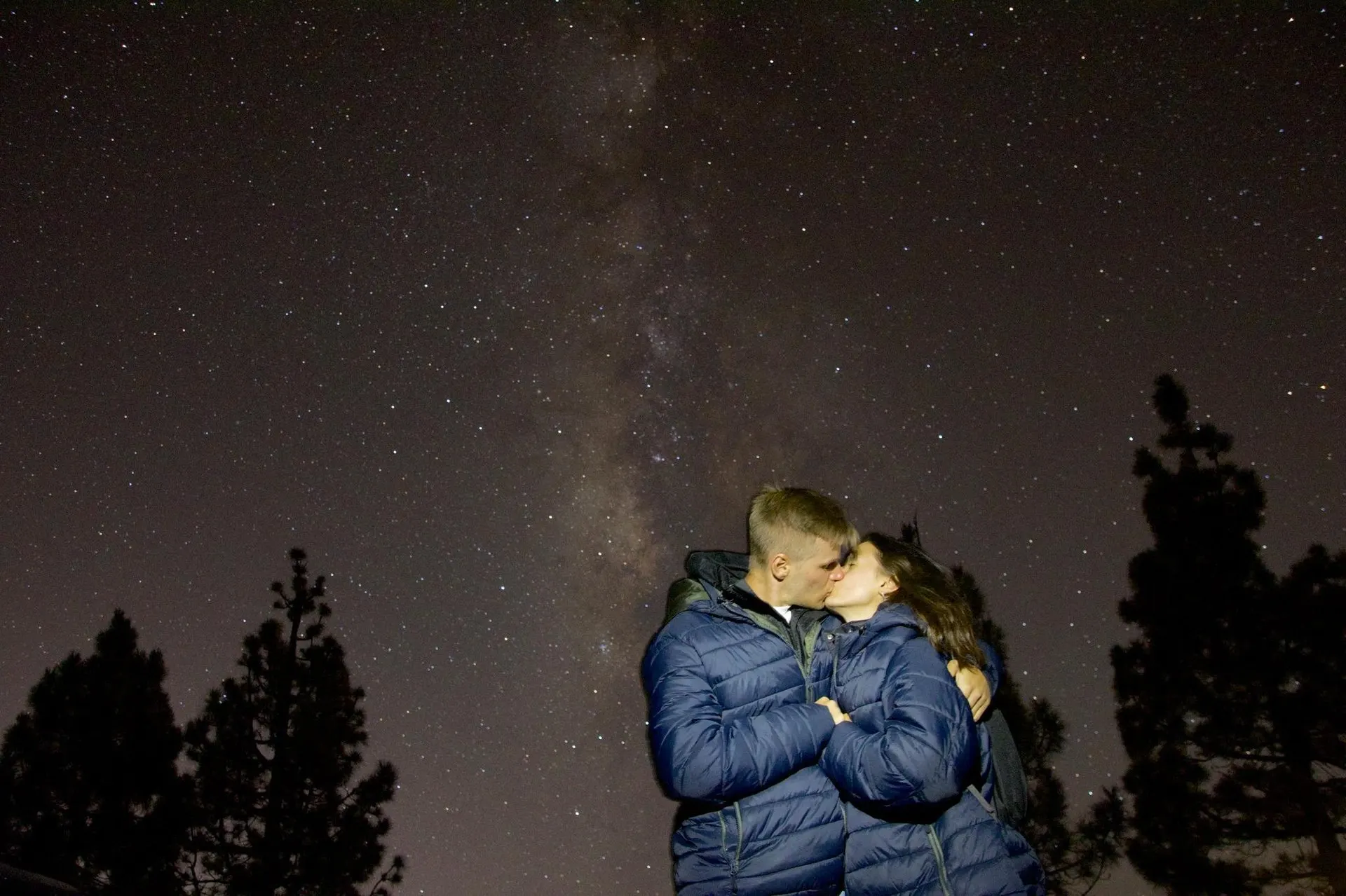 Una coppia abbracciata sotto la Via Lattea tra i pini del Parco nazionale del Teide