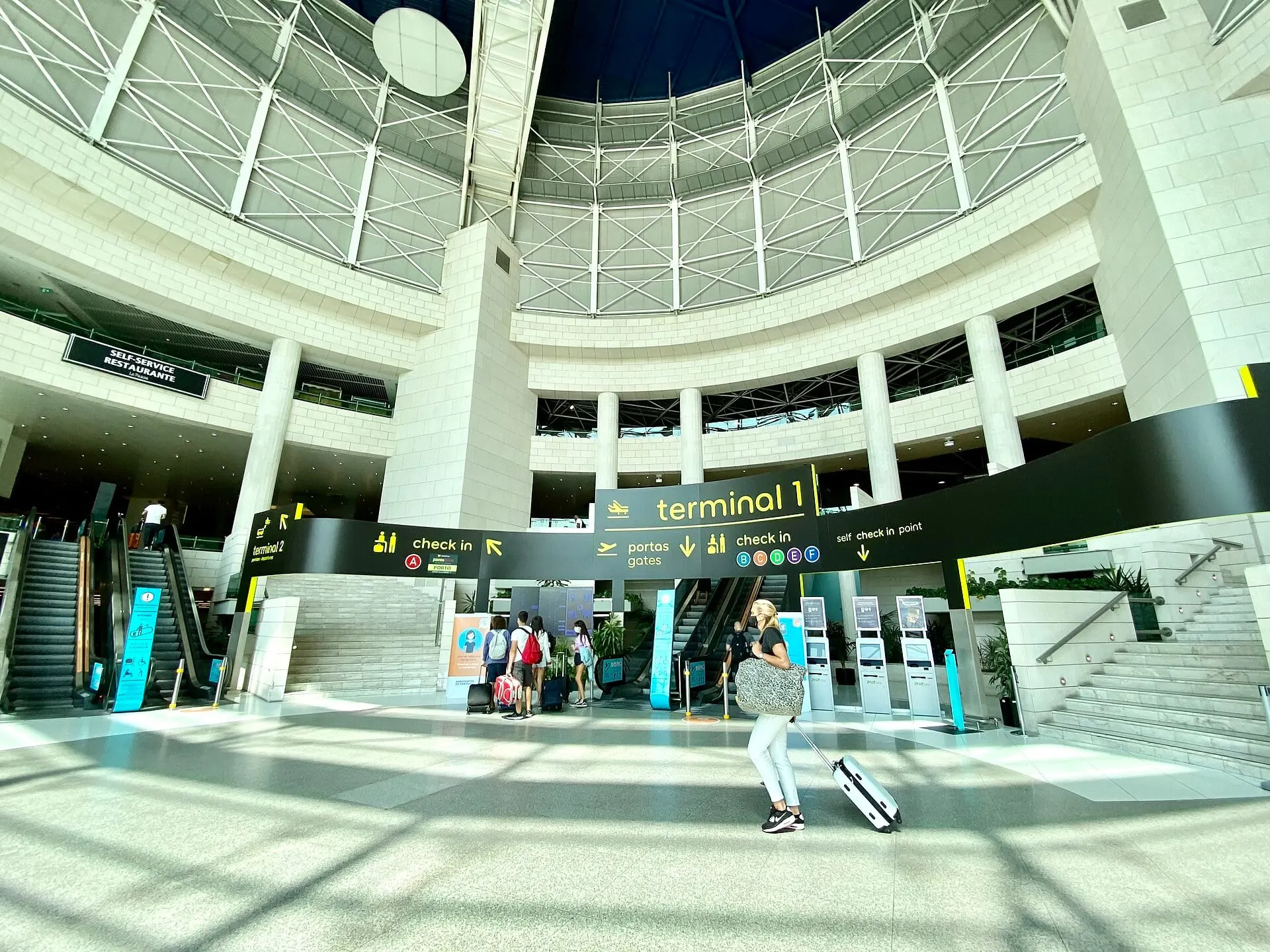 The domed atrium of Terminal 1 at Lisbon Airport, with signs to check-in and the gates