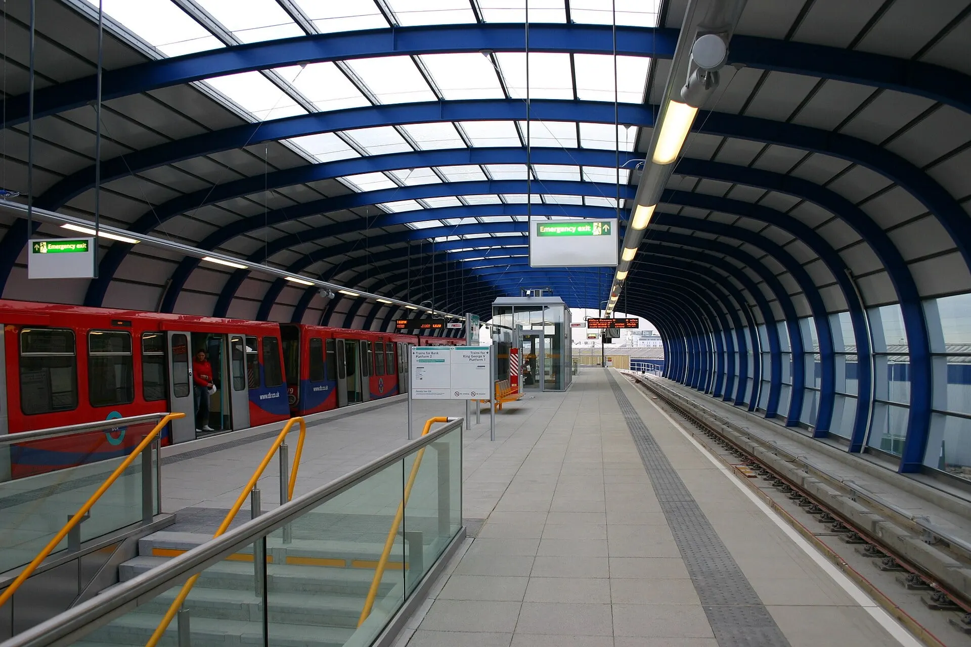 A DLR train at London City Airport station, under its curved blue canopy