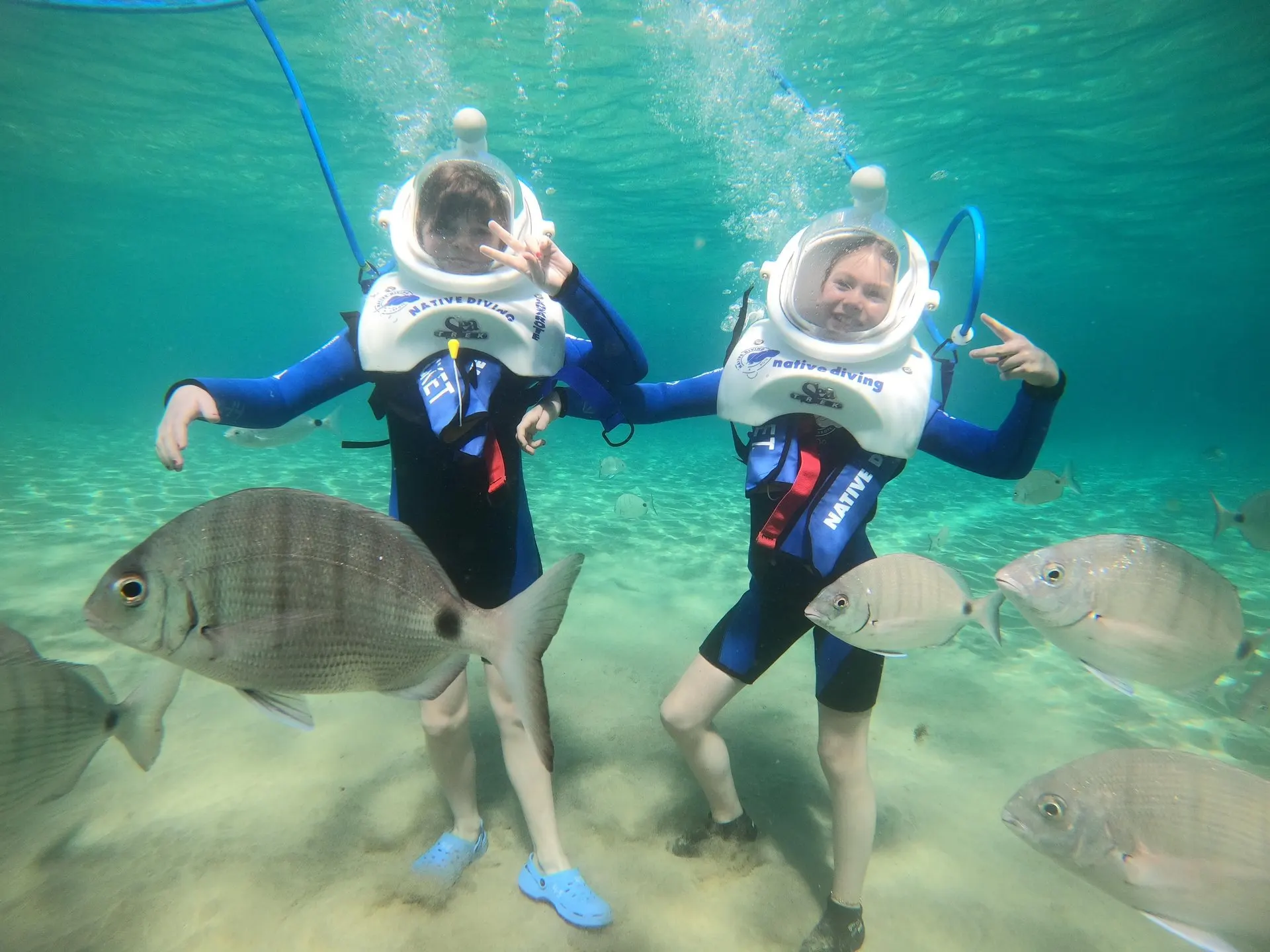 Two young walkers in Sea Trek helmets with fish around them