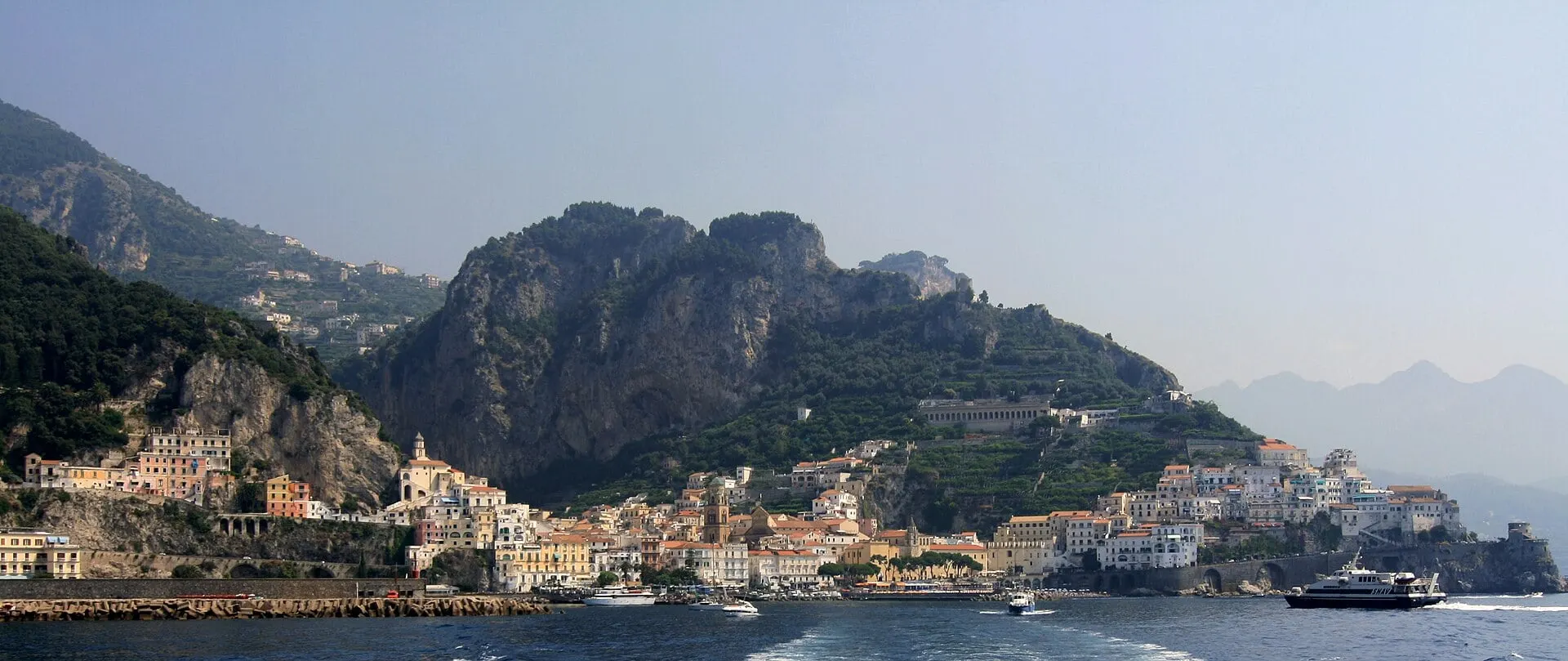 Amalfi from the sea under its mountain, with a ferry heading for the harbour