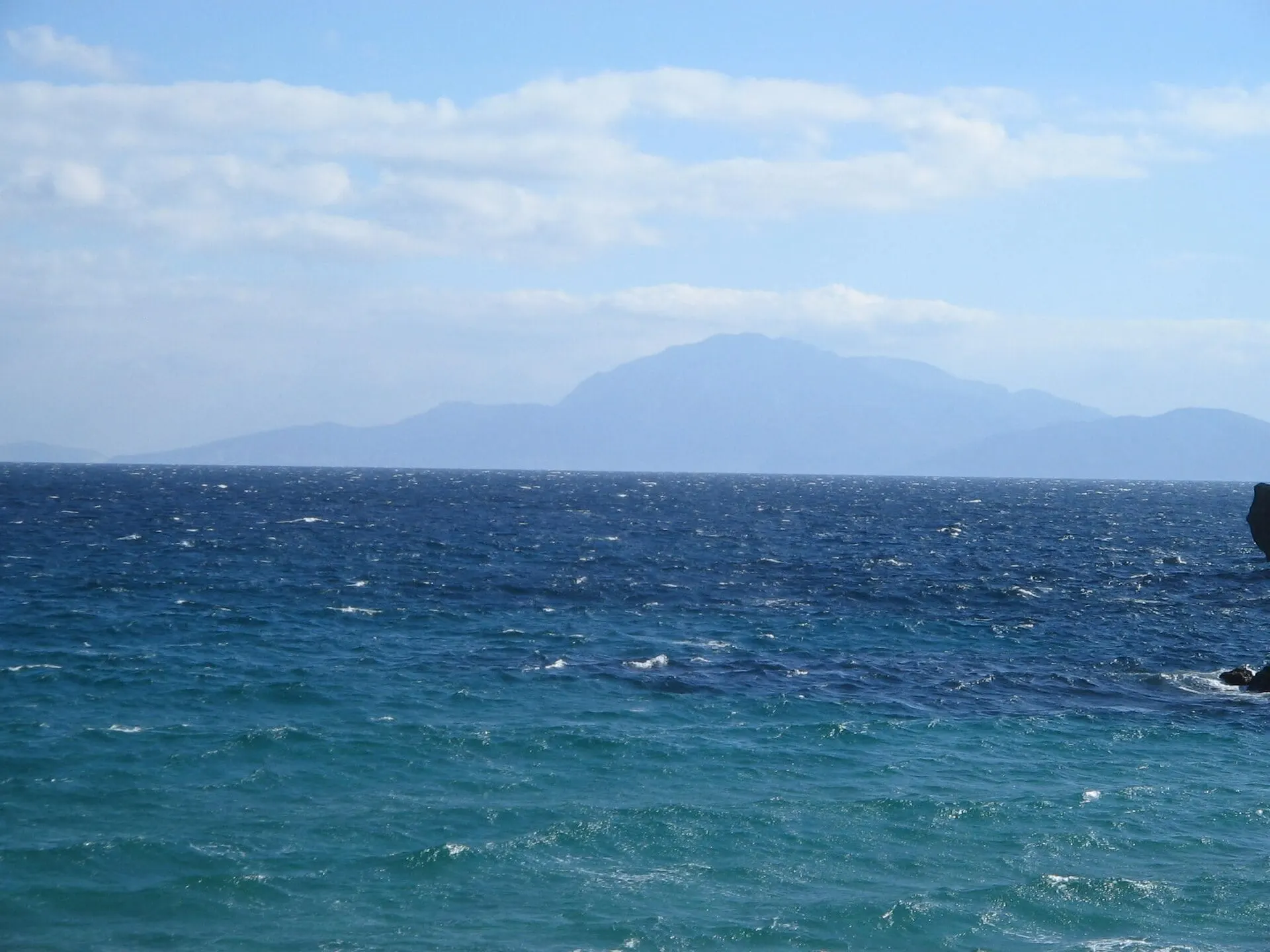The blue water of the Strait of Gibraltar with the Moroccan coast on the horizon, seen from Tarifa