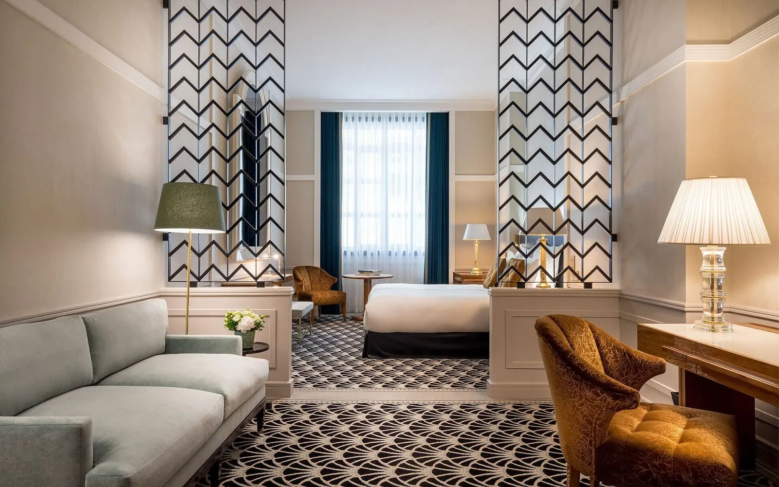 Deluxe Suite at The One Monumental Palace: a sofa and armchair in the sitting area, with the bed beyond a patterned screen