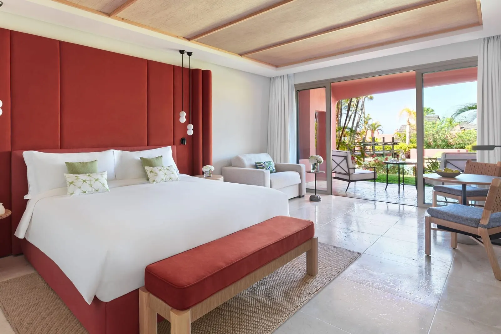 Retreat Deluxe Room Garden View at the Ritz-Carlton Abama: a king bed against a red headboard wall, doors to the terrace