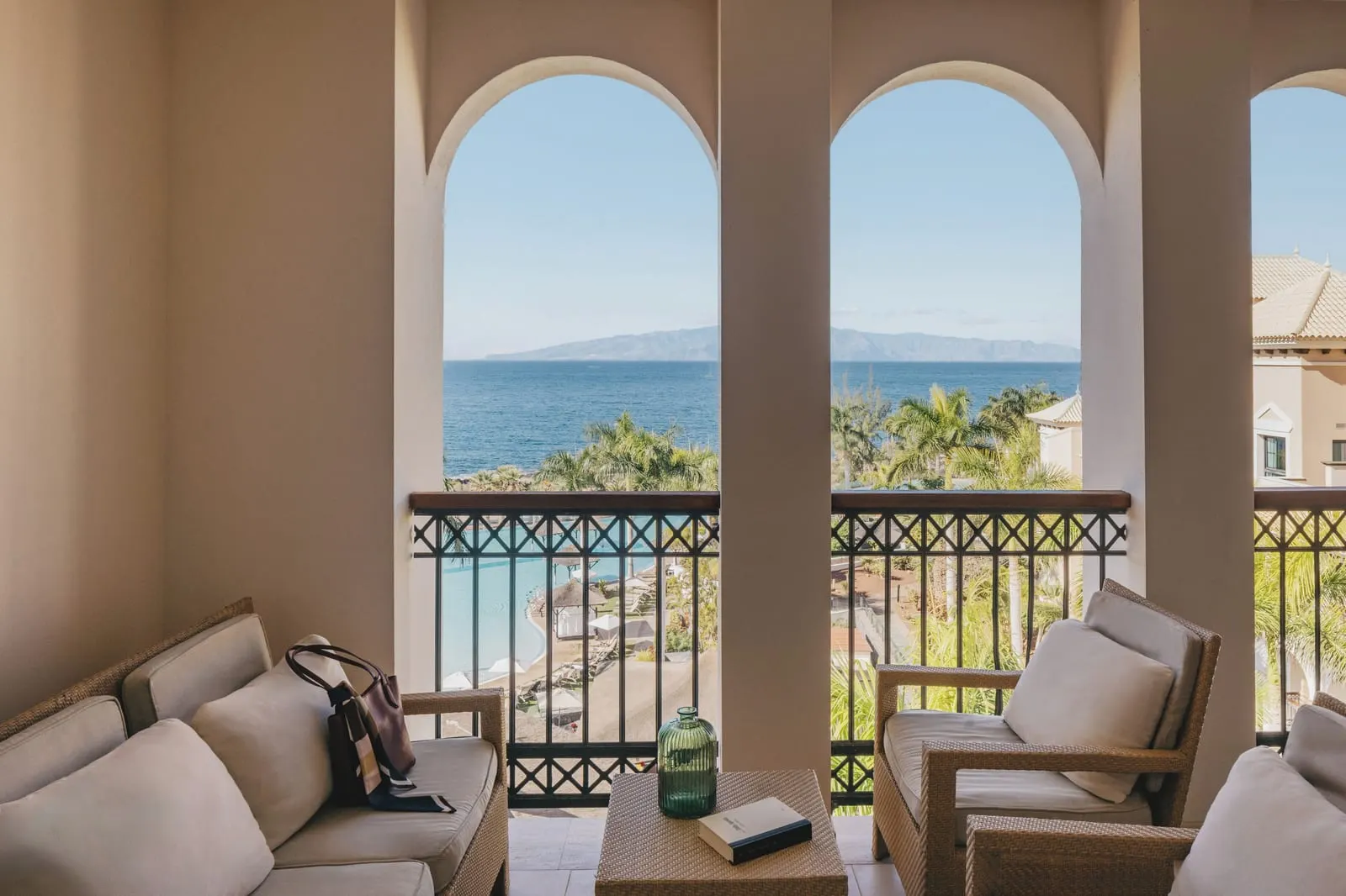 RedLevel Junior Suite Ocean Front balcony at Gran Meliá Palacio de Isora: seats behind arches, with the sea and an island beyond