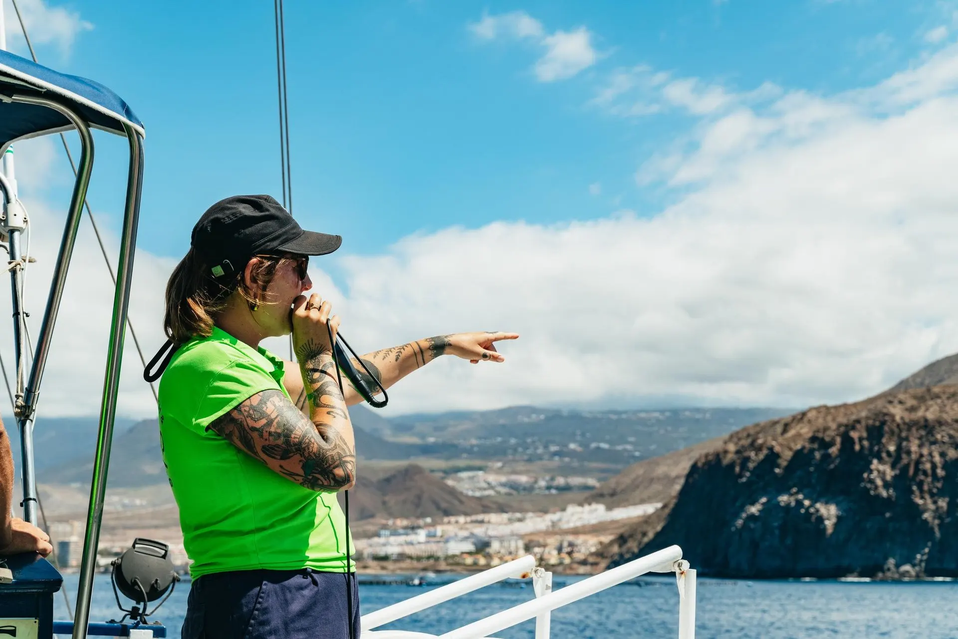 The guide pointing out whales from the deck, with the south coast behind